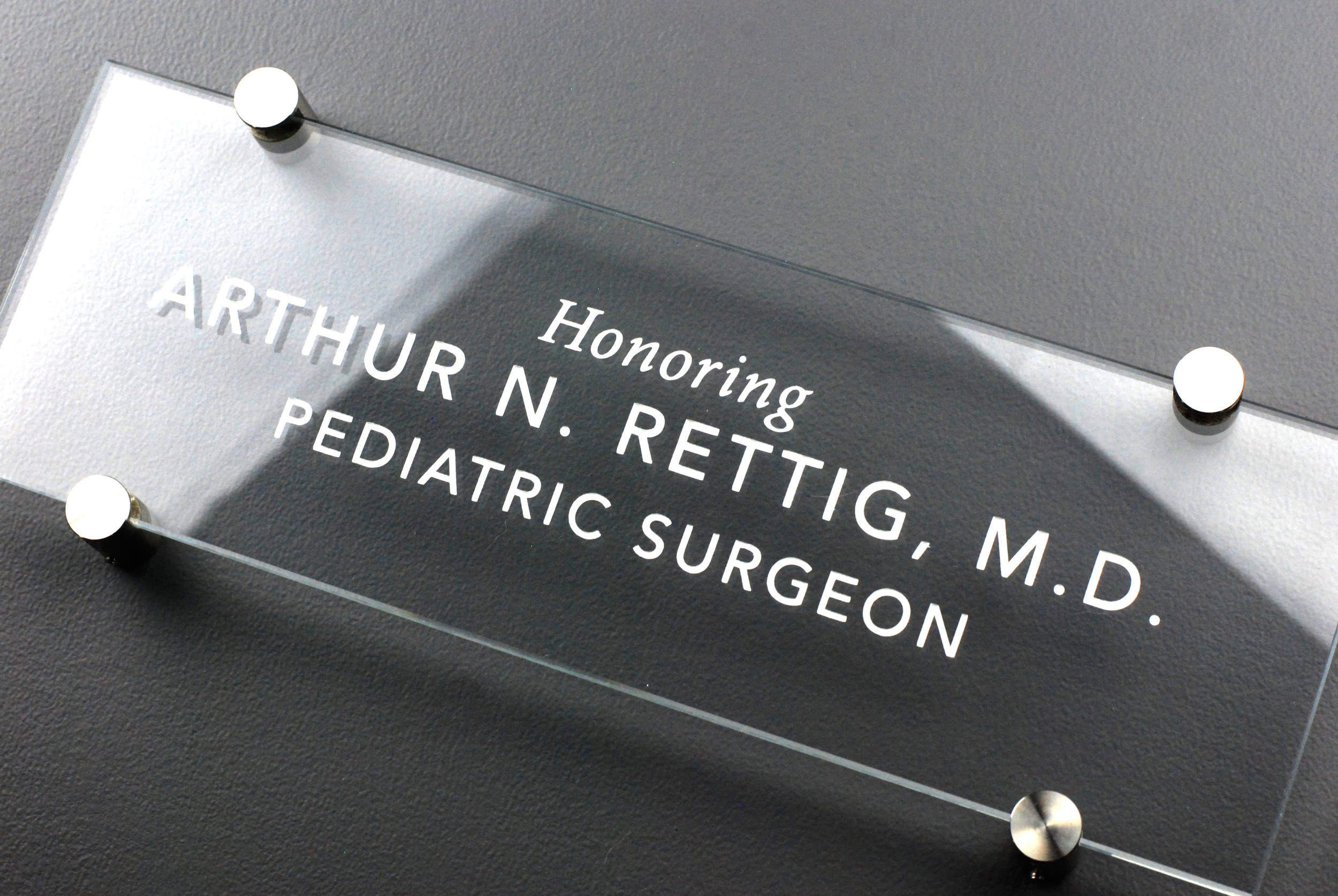 Clear glass sign with painted text and stainless steel hardware.