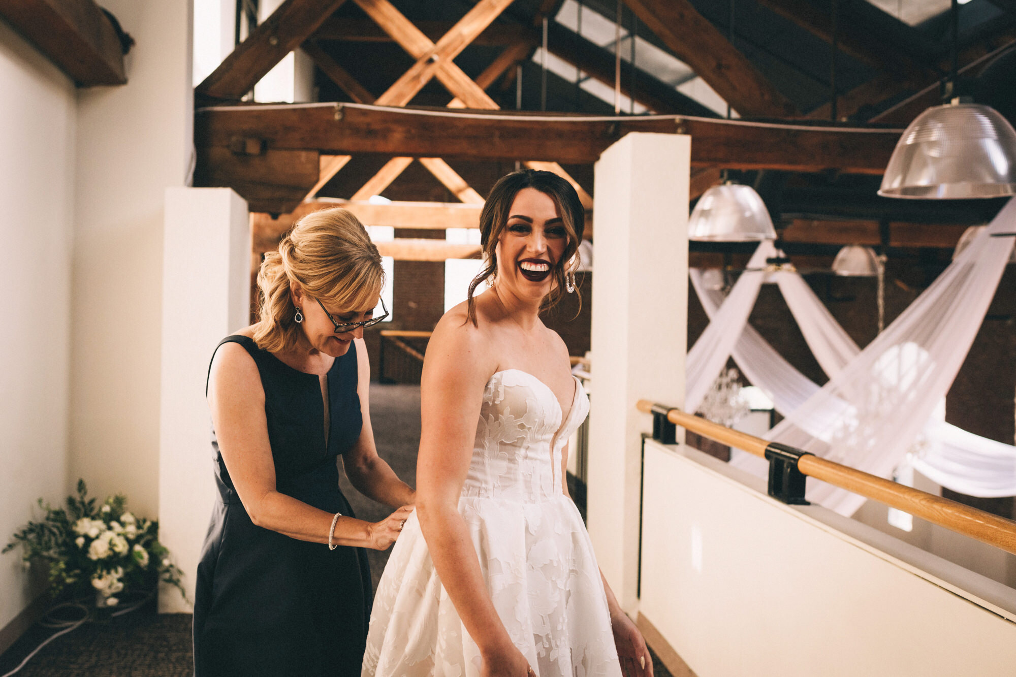  Allison laughs as her step-mother zips up her wedding dress 