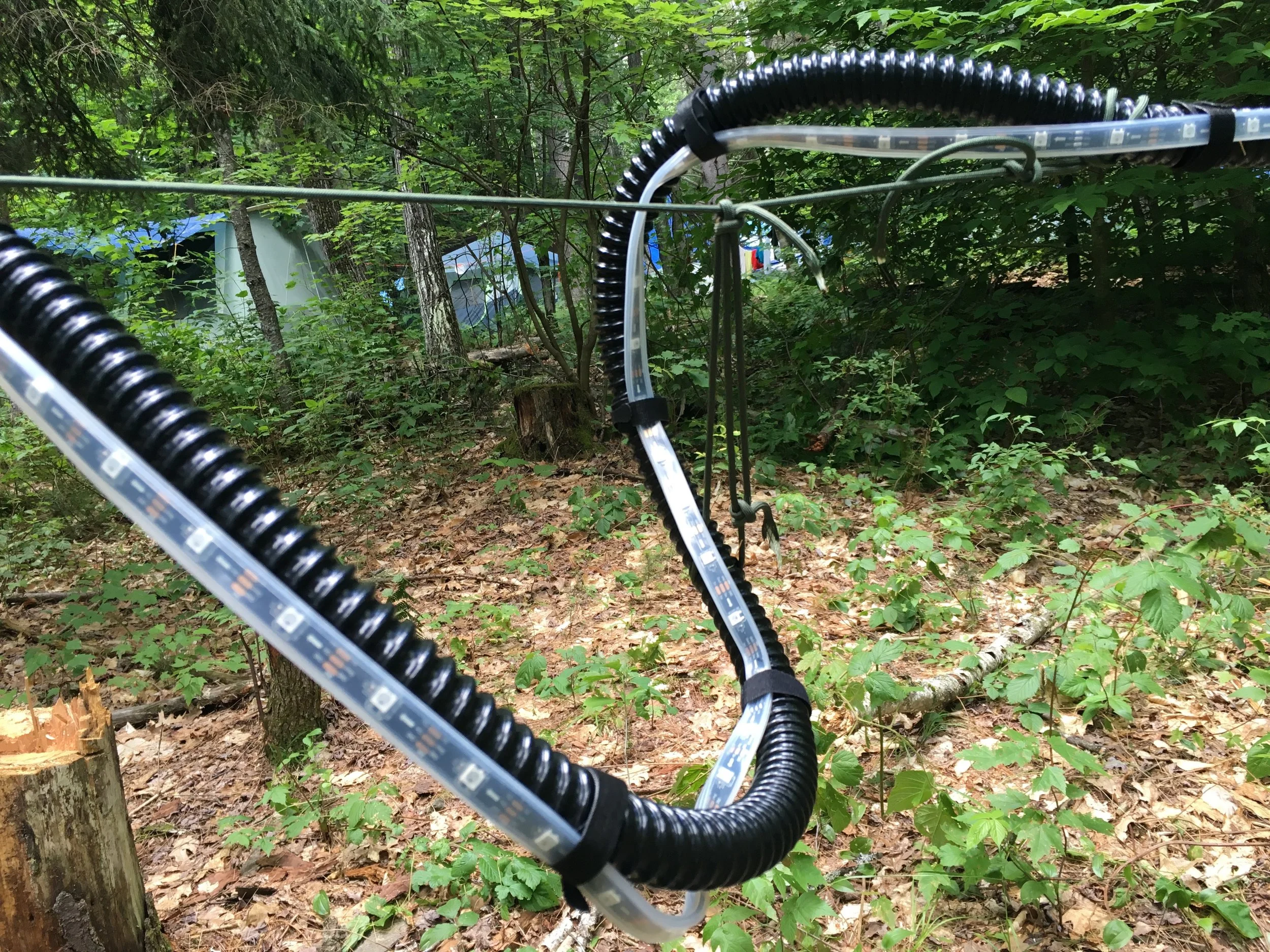 The flexible conduit has enough structural strength that it allows the creation of mid-air loops like this one above. Concept sketches and the first prototype deployment (below) had the lights positioned overhead. As it turns out, people don't really look up. Especially in the woods, at night. Later installations stayed at just over eye level, or lower.