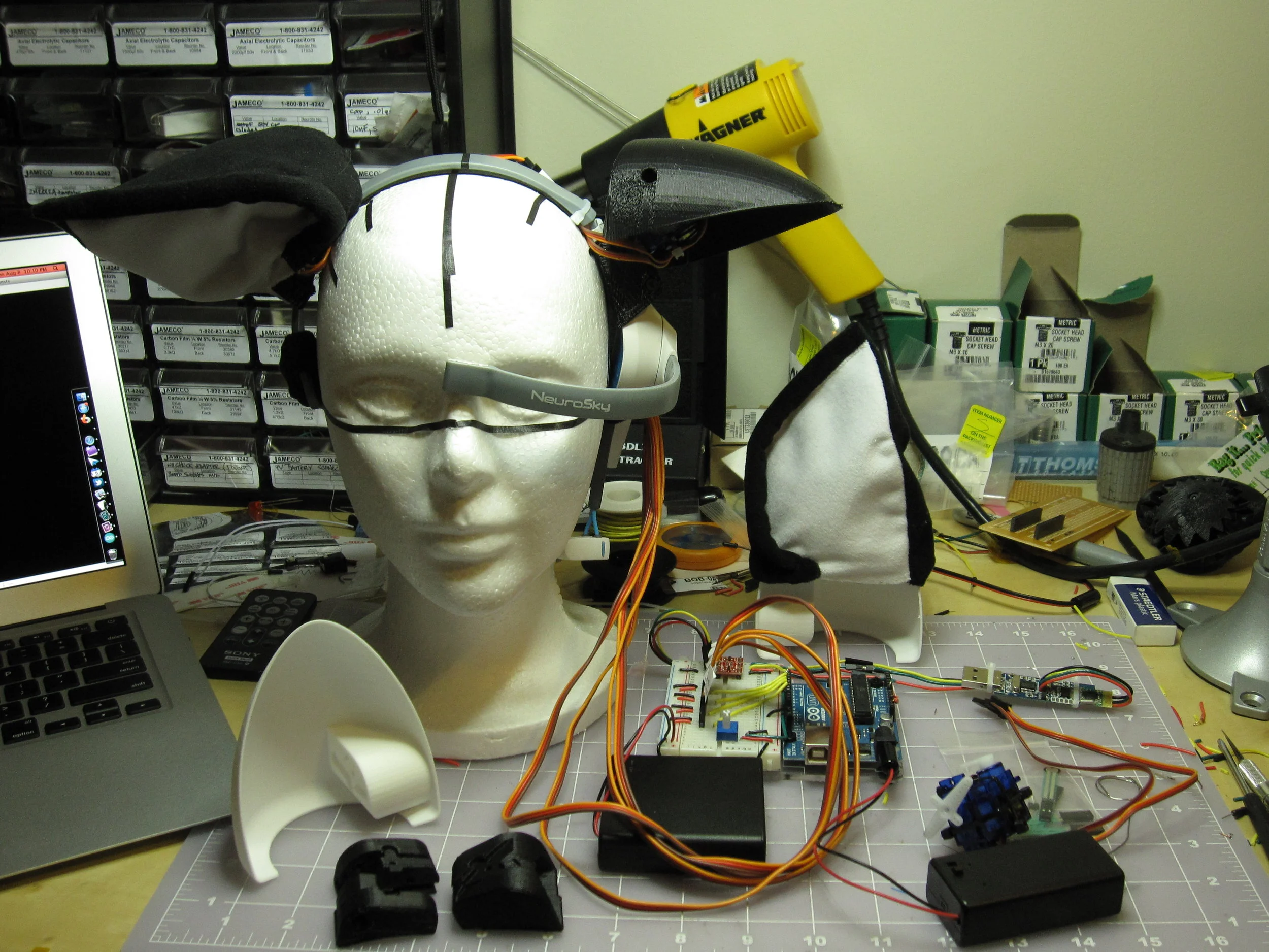  Above: the fully-functional EEG animation test rig on the workbench.  (Also shown is the fabric ear covers, sewn for me by my generous friend Miriam Byroade.)  Below: video of the first time controlling the ears with a MindWave headset (which is off