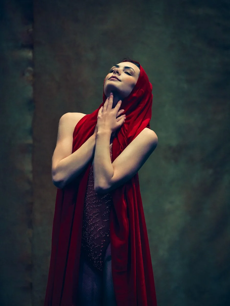 This fine art portrait explores the emotional power of the color red, symbolizing devotion, strength, and quiet surrender. Draped in rich crimson fabric, the subject’s upward gaze and prayer-like pose evoke an angelic, contemplative presence. The res