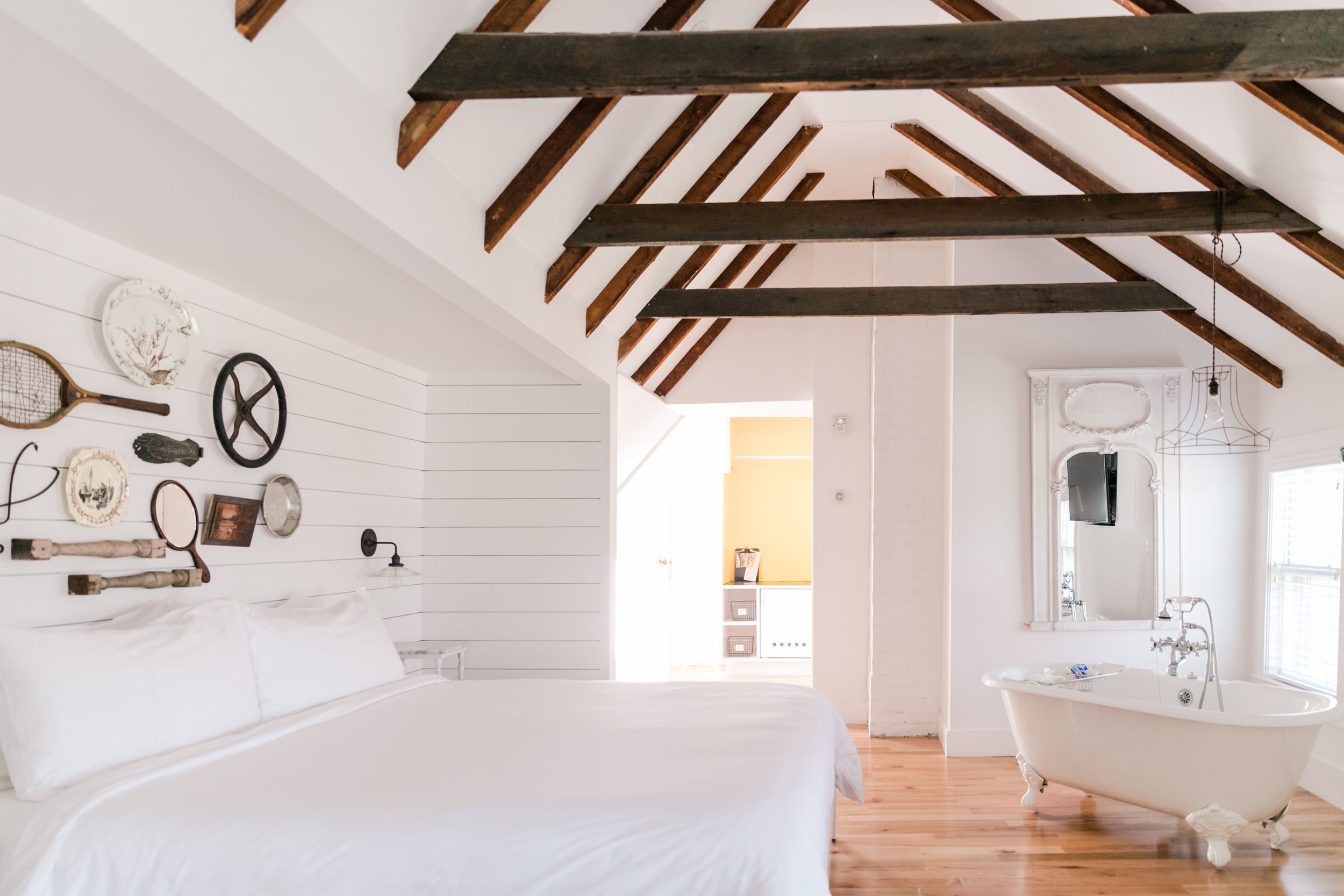 Loft style hotel room with white bed, gallery wall