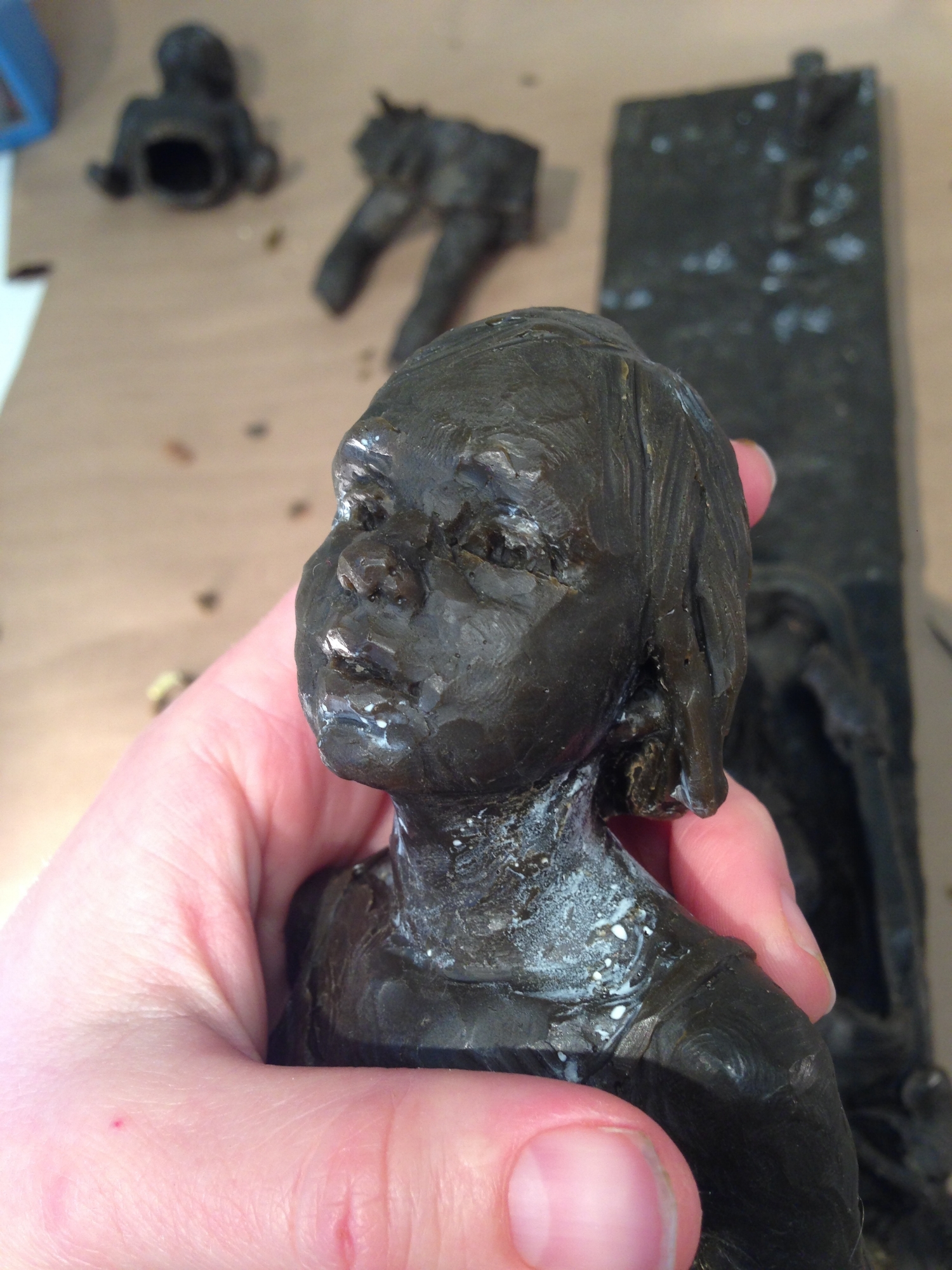 Mardie holding the wax cast of the girl while cleaning up imperfections in the wax as part of the process in bronze casting. 