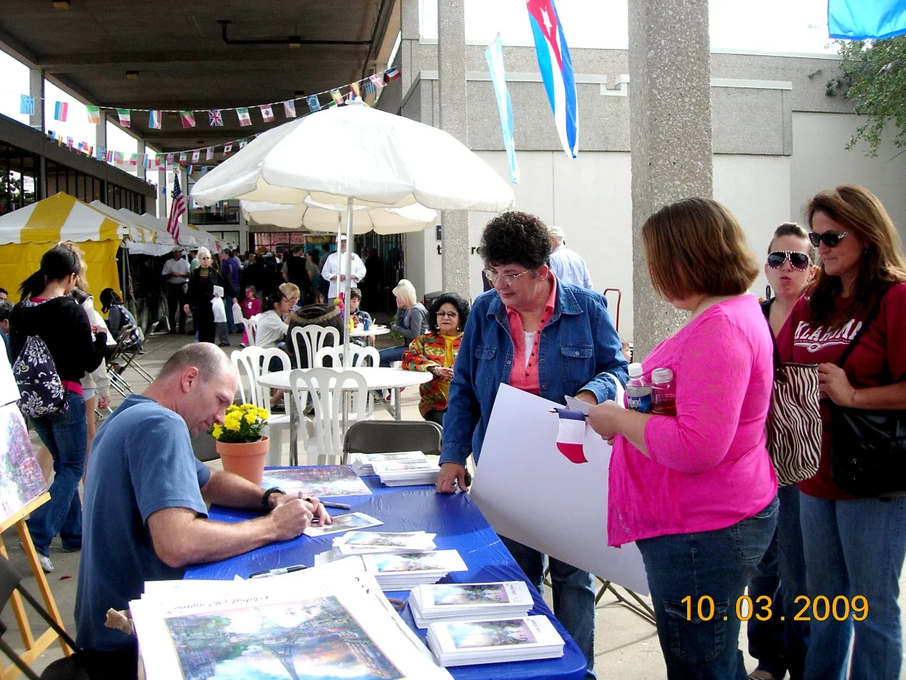 Jonathan signing posters at 2009 Global Oklahoma. Food Court in background.