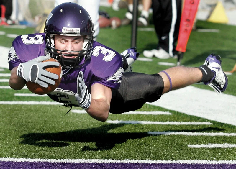 Warhawk wideout Aaron Rusch dives in for a touchdown to put Whitewater up 28-7 early in the second quarter. The Warhawks dominated the Lakeland College Muskies 70-7 at Perkins Stadium in the first round of the NCAA Div-III football playoffs. The team went on to win the Div-III national championship.