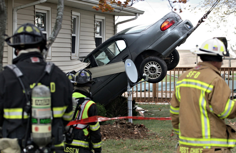  Firefighters look on as a Chevy Malibu is hoisted out of the home at 2972 Route 23, just south of Genoa on Tuesday, Oct. 26, 2010. 