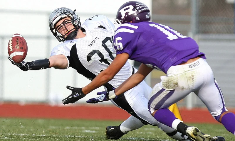  Kaneland running back Jesse Balluff reaches to try and make a one-handed catch against the defense of Rochelle linebacker Roman Martinez in the third quarter at Rochelle Township High School in Rochelle, Ill. on Saturday, Nov. 12, 2011. Kaneland def
