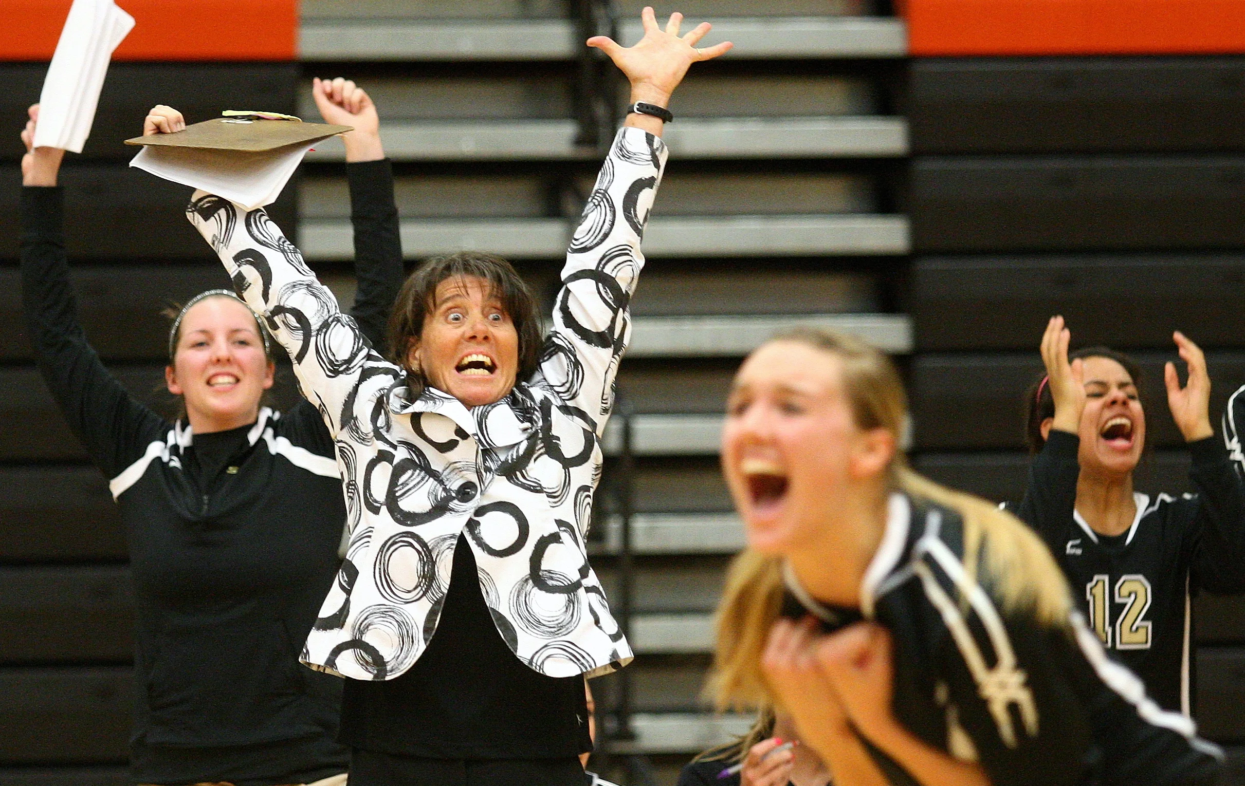 Sycamore coach Debbie Klock celebrates the match-winning point along with Ratasha Garbes (foreground) and Mattie Hayes (12) as Sycamore defeats DeKalb 28-26, 25-21at DeKalb High School on Thursday, Oct. 4, 2012. The Spartans lost the five previous matches against the Barbs.