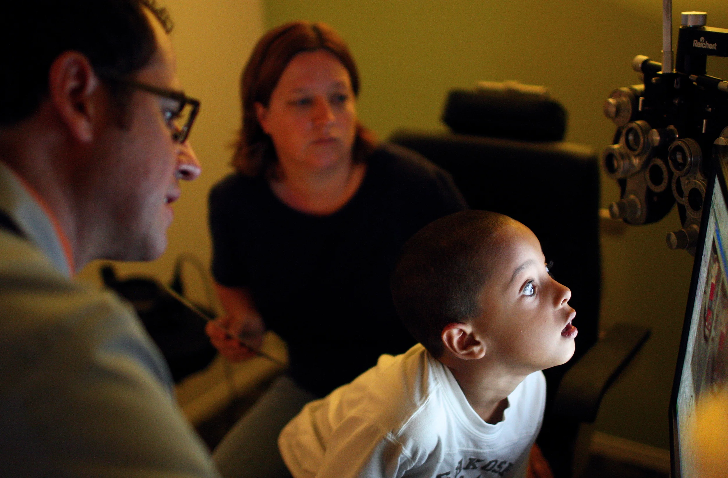   T.J. McNeal, of Kirkland, leans in for a closer look at a computer screen where Dr. Jeffrey Frank of Spex Expressions shows pictures to illustrate how a lens might improve his vision on Tuesday, Aug. 14, 2012. Five-year-old T.J., who was accompanie