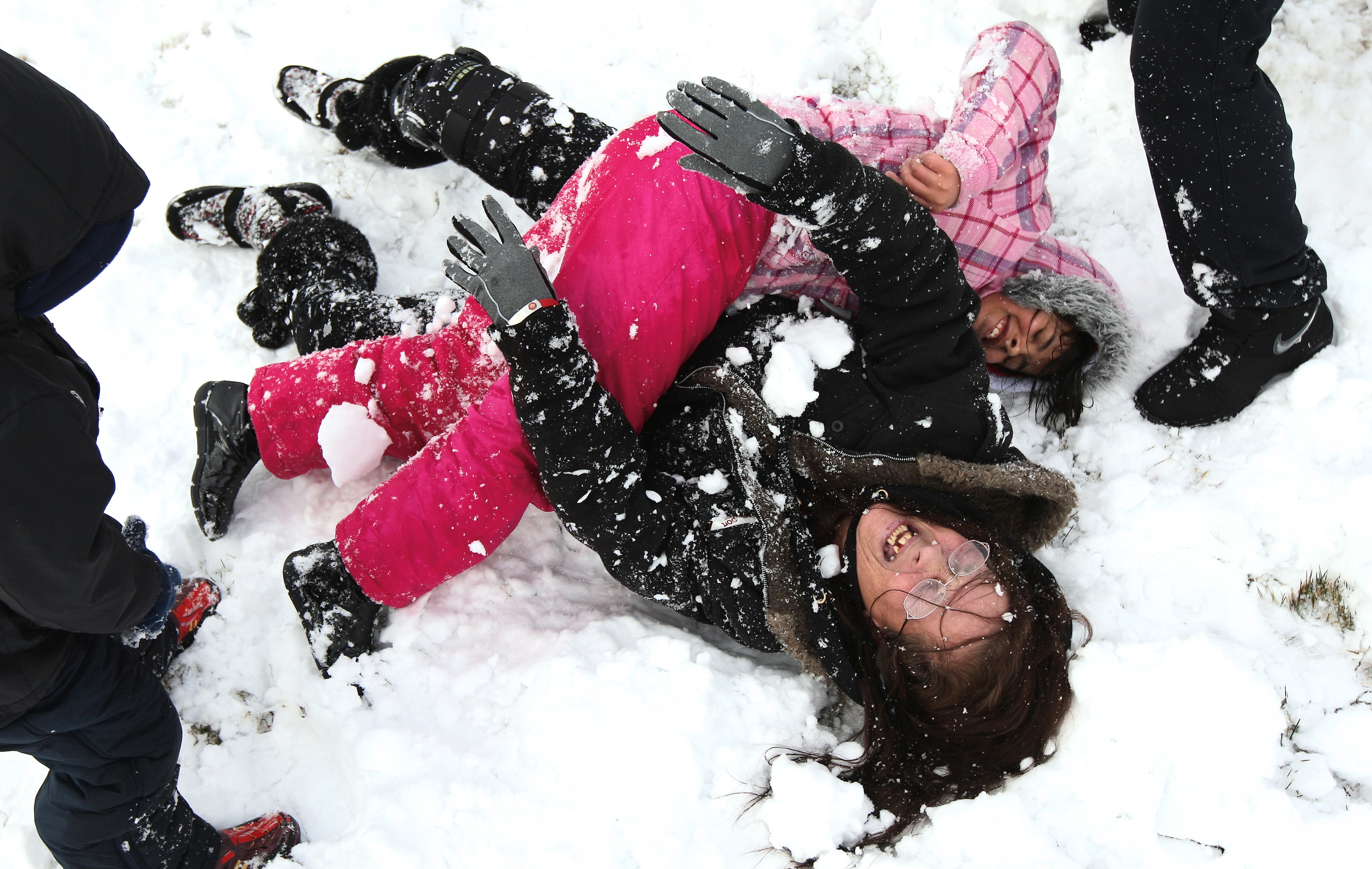   Joann Blough wrestles in the snow with niece Breiona Mendez (top) as Blough's grandson Liam Kaemke (left) and nephew Brandyn Rosario (right) ambush the pair with snowballs in front of Liam's home in DeKalb, Ill. on Friday, Feb. 24, 2012. Blough sai