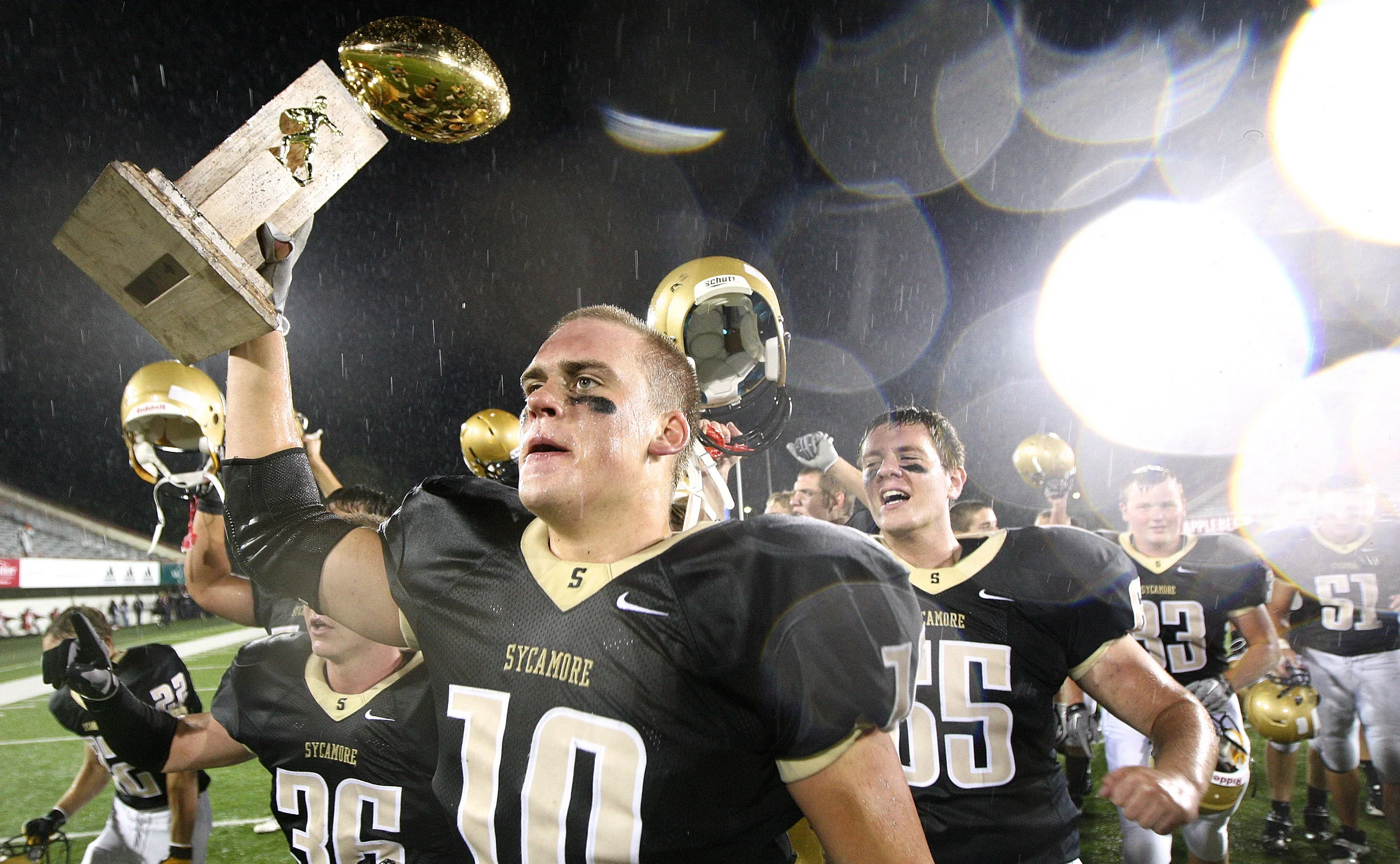 Sycamore's Jordan Kalk, trophy in hand, leads the victorious Spartans to their fan section after beating DeKalb 33-22 in their annual matchup at Huskie Stadium in DeKalb, Ill. on Friday, September 9, 2011.