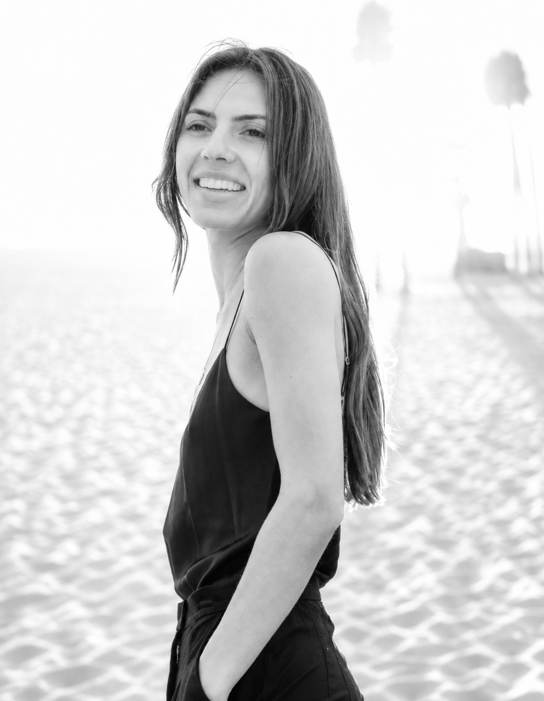 Portrait of a smiling woman with long brown hair wearing a black blazer against a plain white background.