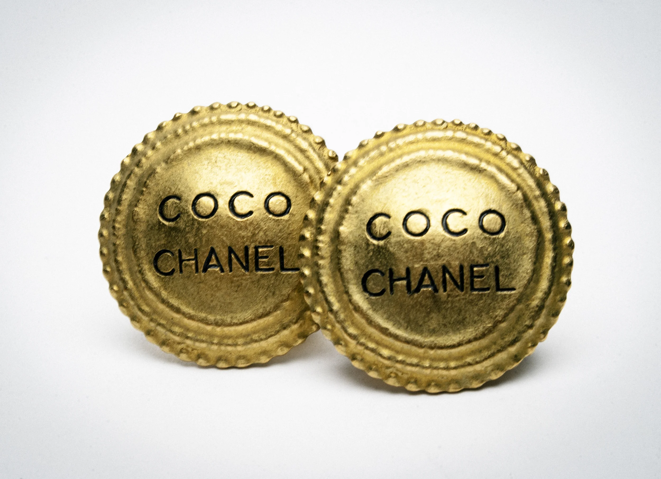 Two circular gold buttons with the text "Coco Chanel" engraved on them.