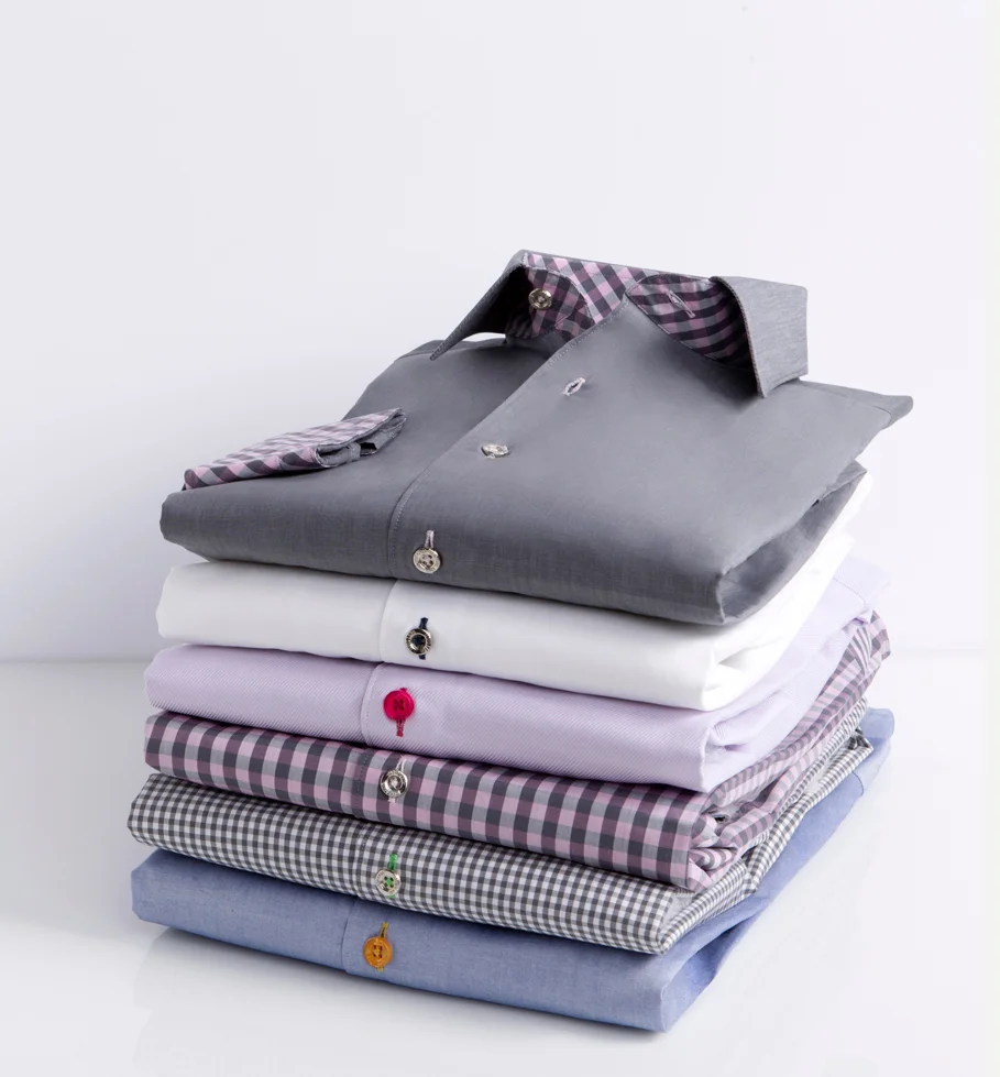Stack of folded men's dress shirts in various colors and patterns