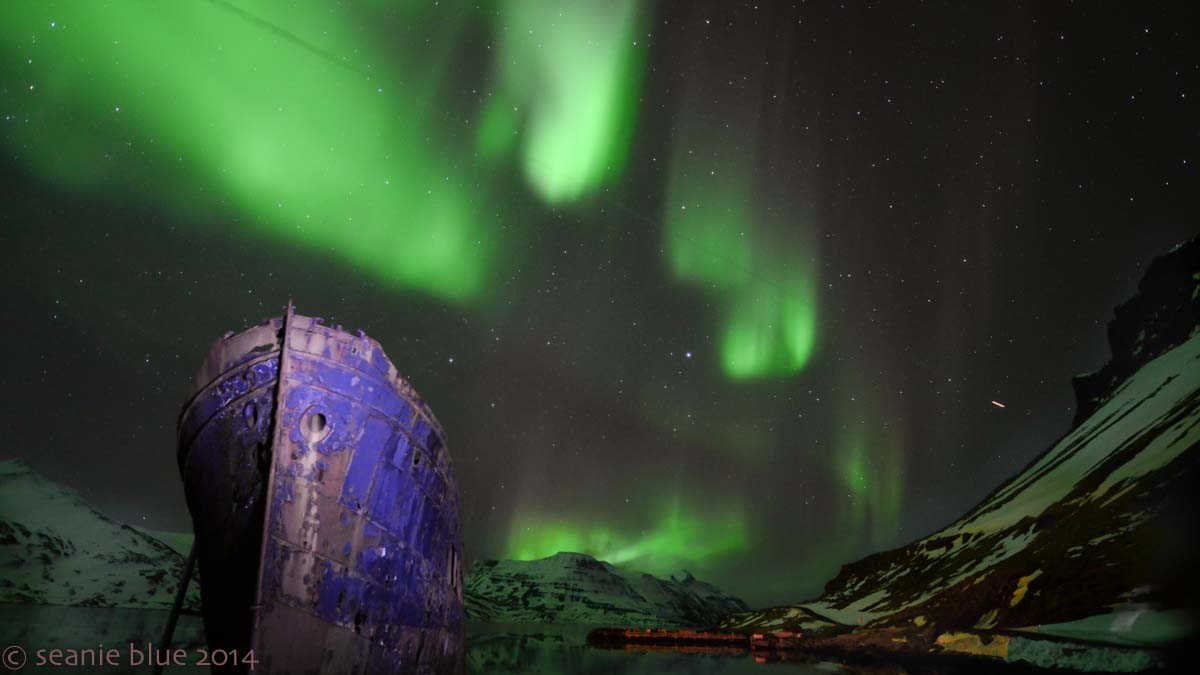 In Djupavik with the abandoned herring ship as an airplane flies in front of the Aurora.