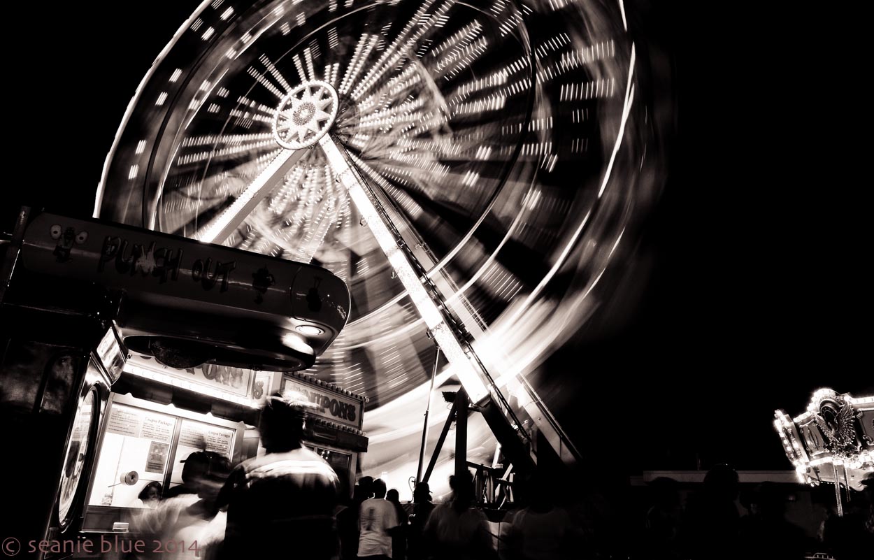 The ferris wheel is the action, blurred by a slower exposure, but the people in the foreground give the picture its life.