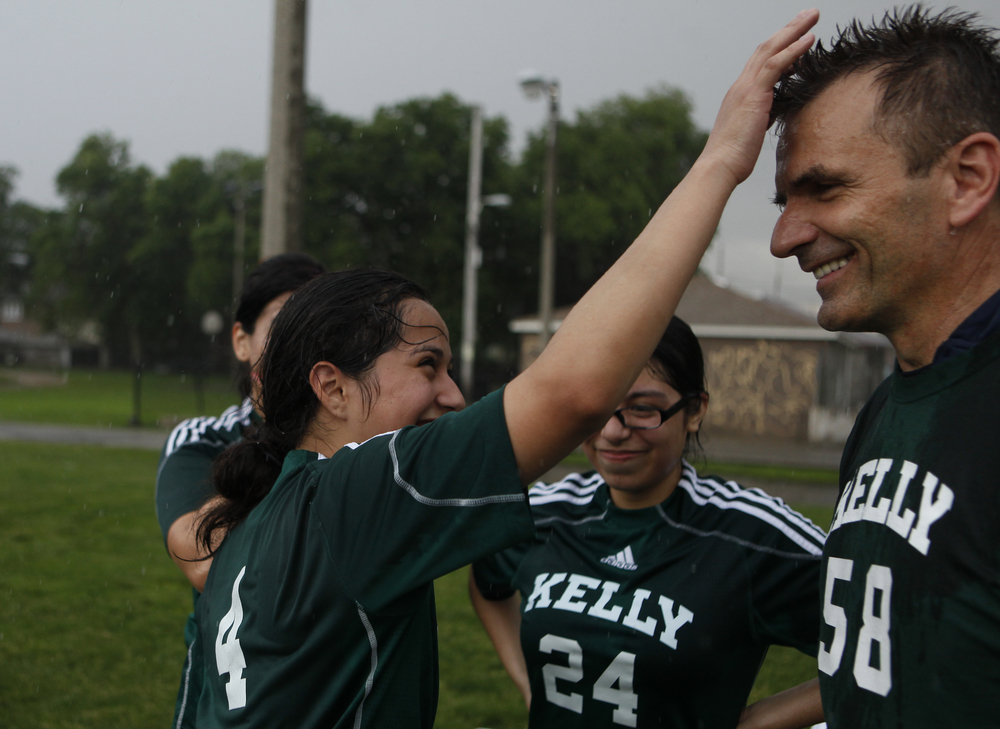  Edith Garcia, a sophomore, spikes Head Coach Stan Mietus' hair after a rainstorm during practice in front of the Kelly High School in Chicago on Tuesday, June 11, 2013. &nbsp;The Kelly High School girls varsity soccer team is almost entirely first-g