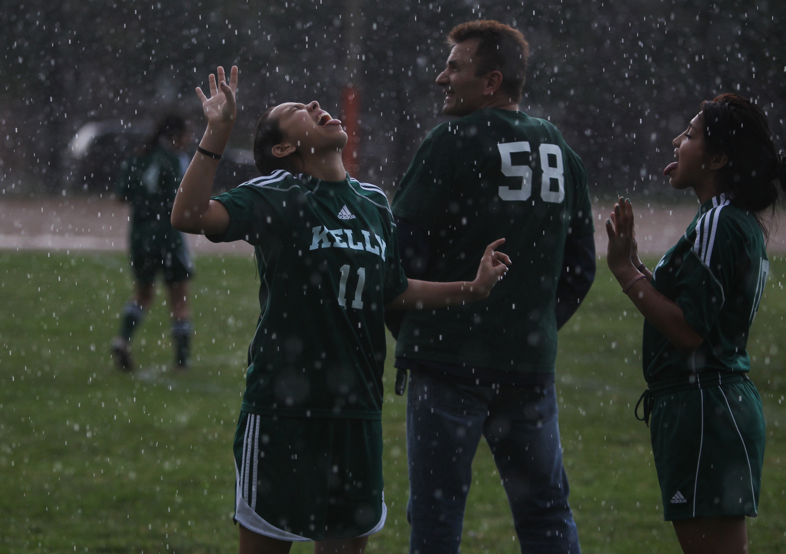  Jennifer Medina, left, and Marbella Rodriquez play in the rain behind their coach, Stan Mietus, during practice in front of the Kelly High School in Chicago on Tuesday, June 11, 2013. &nbsp;The Kelly High School girls varsity soccer team is almost e