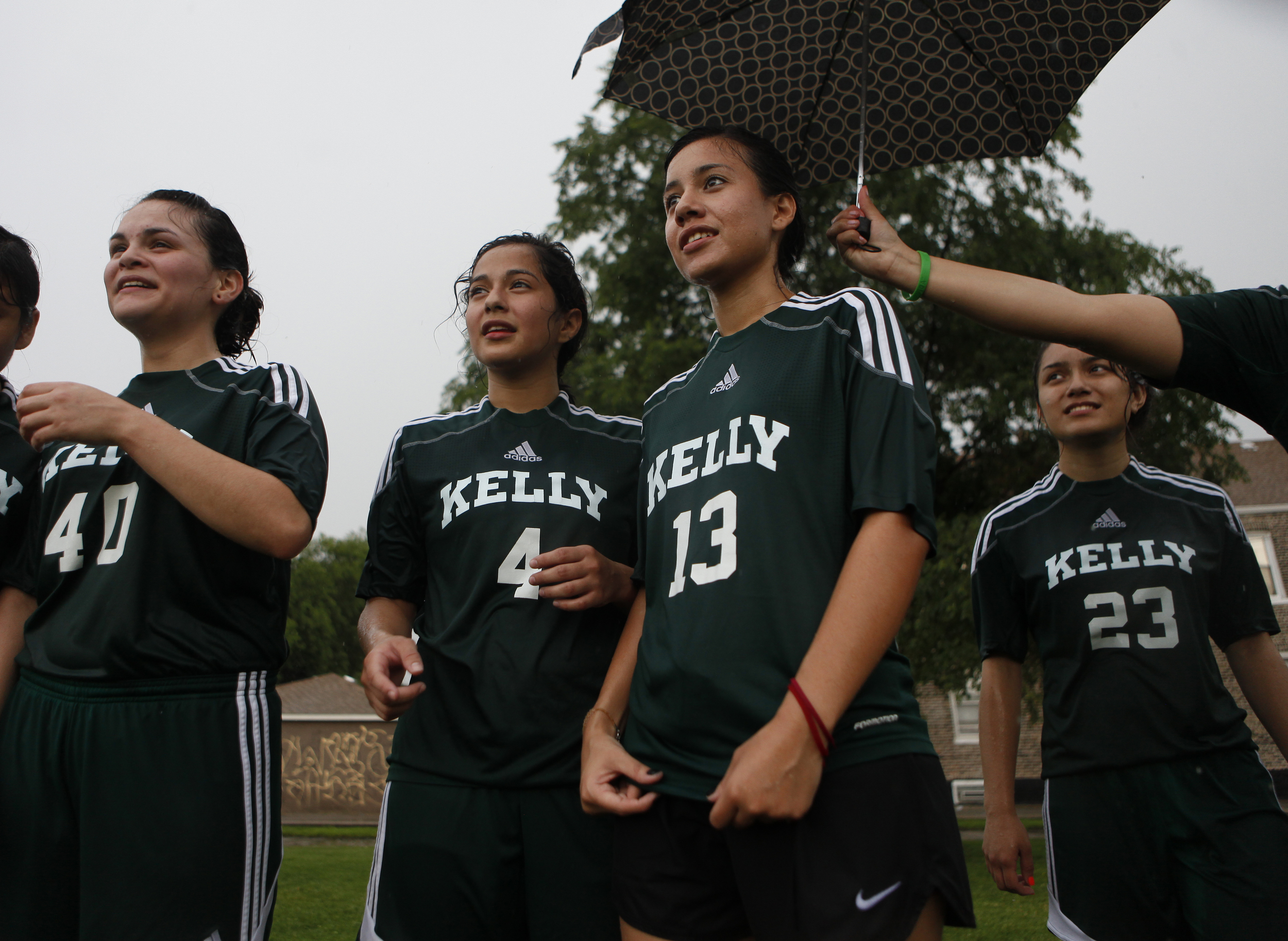  Cynthia Lucio, a junior, holds an umbrella out over Edith Garcia and Ana Flores' heads during practice in front of the Kelly High School in Chicago on Tuesday, June 11, 2013. &nbsp;The Kelly High School girls varsity soccer team is almost entirely f