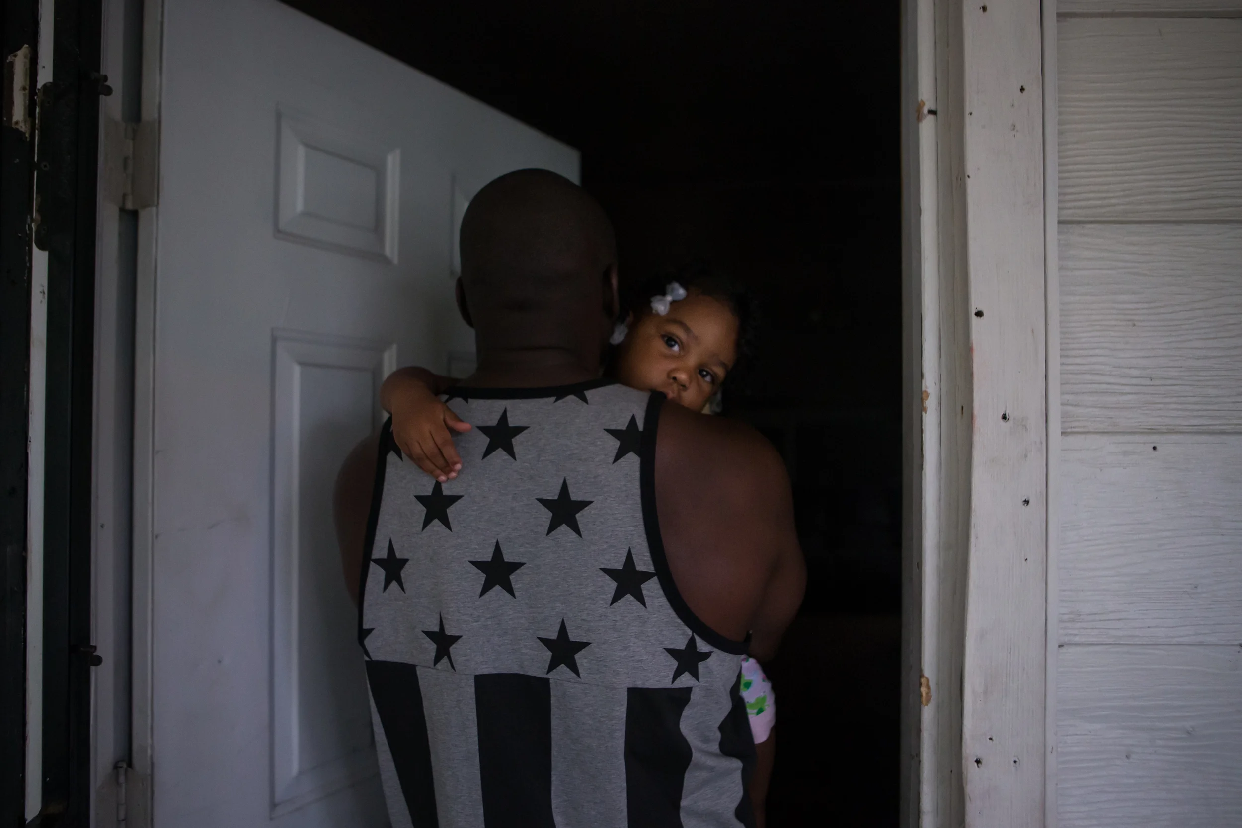     Daniel carries Danielle, his niece, inside his brother David's house on Monday, July 8, 2013. &nbsp;On either side of David's house there are evicted homes where gangs, similar to the one Daniel and David were in years ago, sit with guns in their