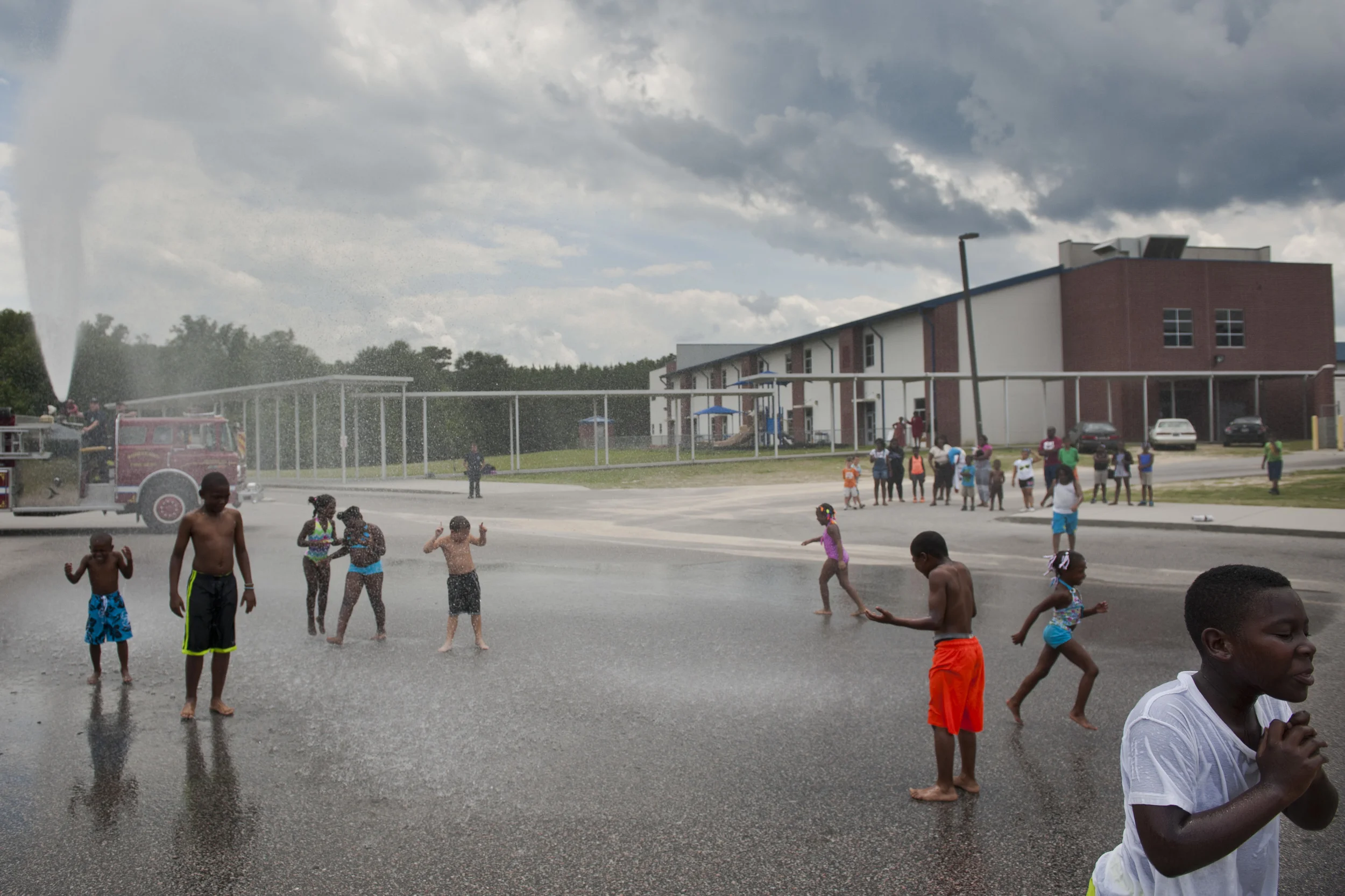 Children in the YMCA Summer Camp play in the spray of a fire hose outside of Ridgeland Elementary School on Wednesday, July 30, 2014. The Ridgeland Fire Department came to the school to teach the children about fire safety. This was the children's reward for getting all of the questions correct on the verbal fire safety quiz. Photographed for Al Jazeera America. 