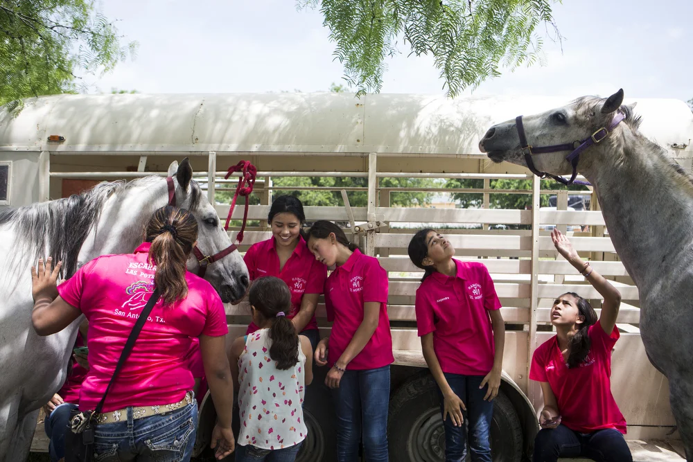 Andrea Murillo rests her head on her sister Roxanna Murillo as Miriam Alejandra Montecillos and Jackie Ayala try to prevent Mora from eating the leaves on the tree branch above their heads. The team was waiting to perform in the "A Day in Old Mexico" Charreada at the San Antonio Charros Association in San Antonio, Texas on April 26, 2015. "I'm not nervous for today," team captain Kristy Escamilla, left, said. "I think that is because we had such a good practice." "But we can't be too confident," Madelyn Monique Montecillos replied. "We still have to ride well."
