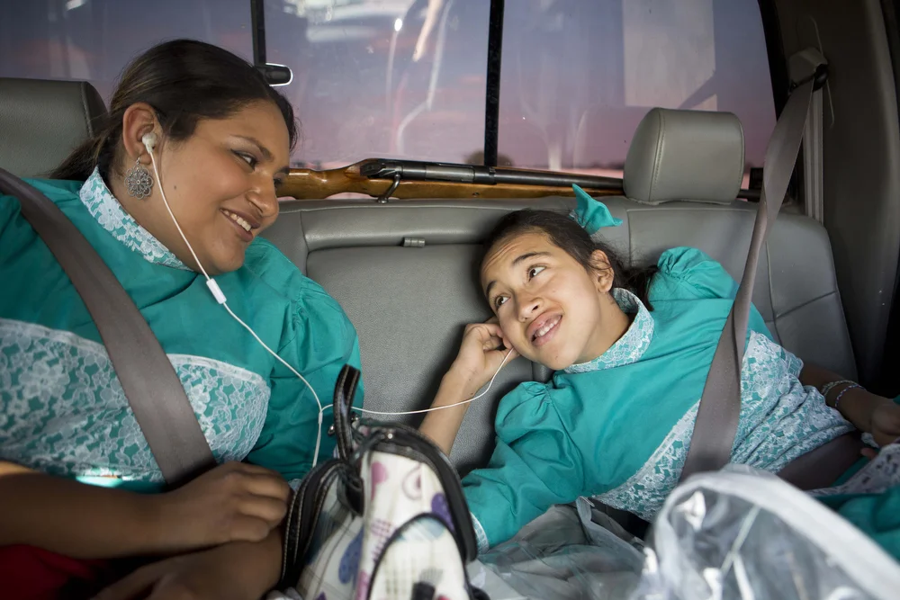 Kristy Escamilla and Jackie Ayala listen to a song together during the drive to Temple, Texas to represent the team at Junta Estatal para Capitanas, or the State Meeting for Captains on February 21, 2015. 