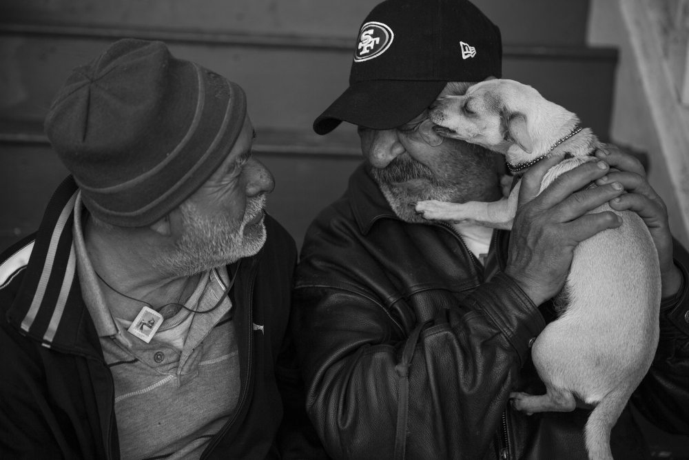 Daniel Dupont watches as Roberto Solarzano gets a kiss from Dupont's dog Mandy while they sit on the stoop of the house Dupont used to live in with his wife in the Mission neighborhood of San Francisco, Calif. on June 3, 2015. Dupont and Solarzano are currently homeless. Dupont's wife died two months ago, leaving him to care for her dog, Mandy. Dupont said he loves Mandy as a way to keep loving his wife. Solarzano has lived in the Mission for 44 years. "Even if you have a job, it doesn't mean you can afford to live here," he said.