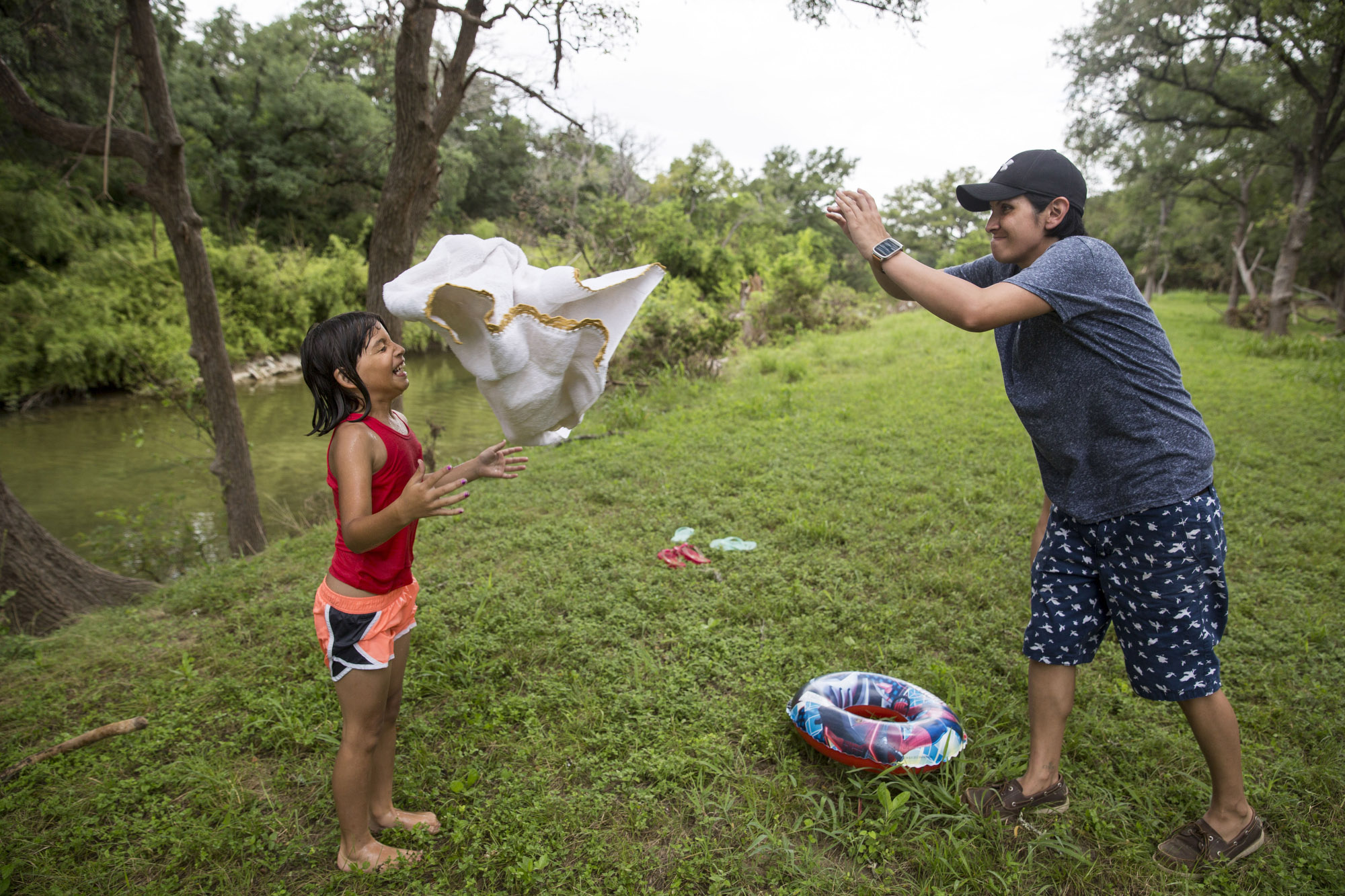 Glenda Bamberger, right, tosses a towel at Serenity Bamberger, 7, after Serenity finished swimming in the Little Blanco River behind their home in Blanco, Texas on July 1, 2015. A month and a half prior, the same river flooded their home destroying the majority of the family's belongings. 