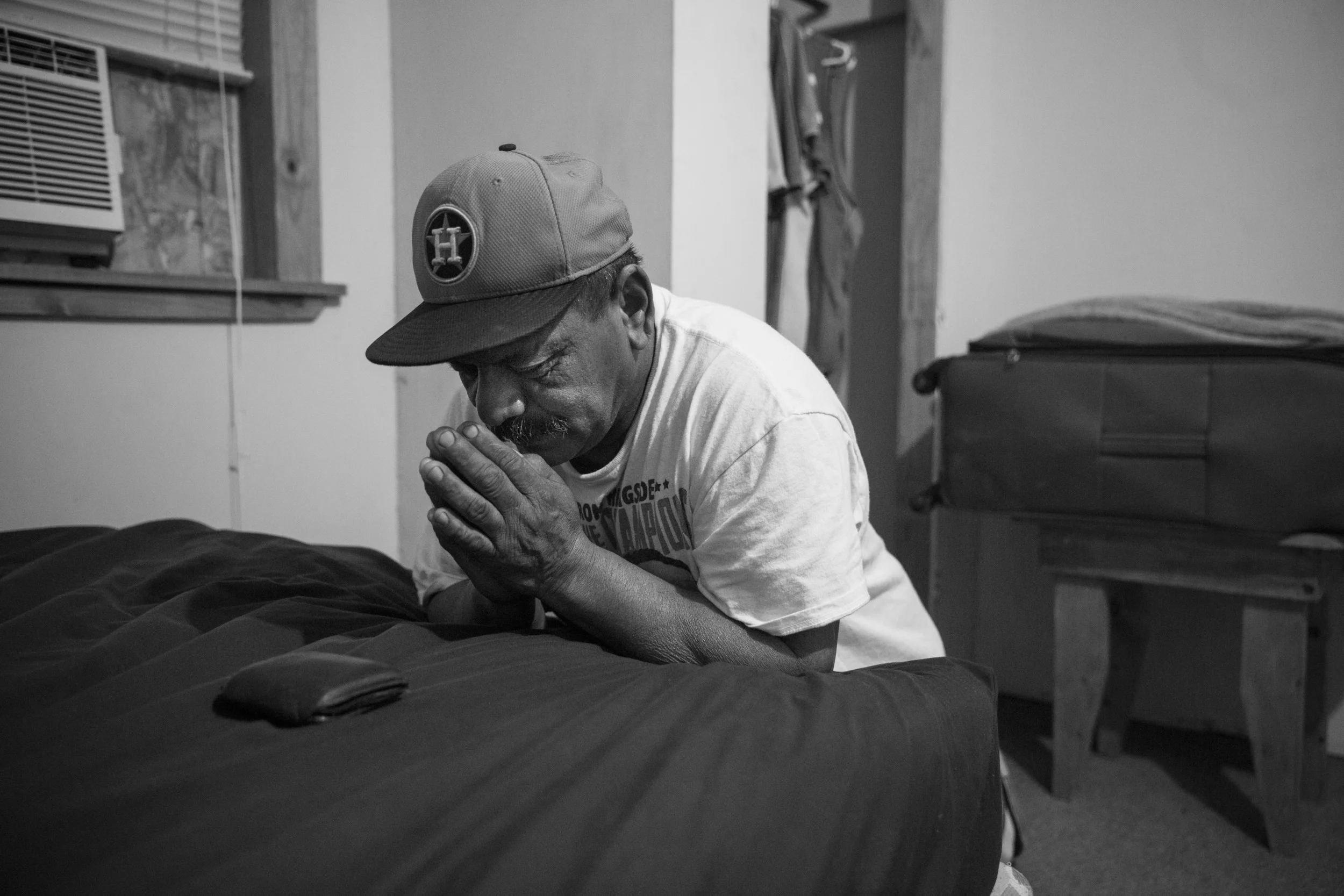 Before dawn Tino Gaona prays in his bedroom on the morning of his youngest daughter's 24th birthday, which he is missing, in Cotulla, Texas on August 6, 2015. "I miss a lot of birthdays and holidays, but that is how it goes," he said. He prays every morning before going to work in the oil field. After 20 years in the oil field, he considers it very dangerous work. Of God, he said, "He's the reason I am still here, so I pray for everybody on my crew."
