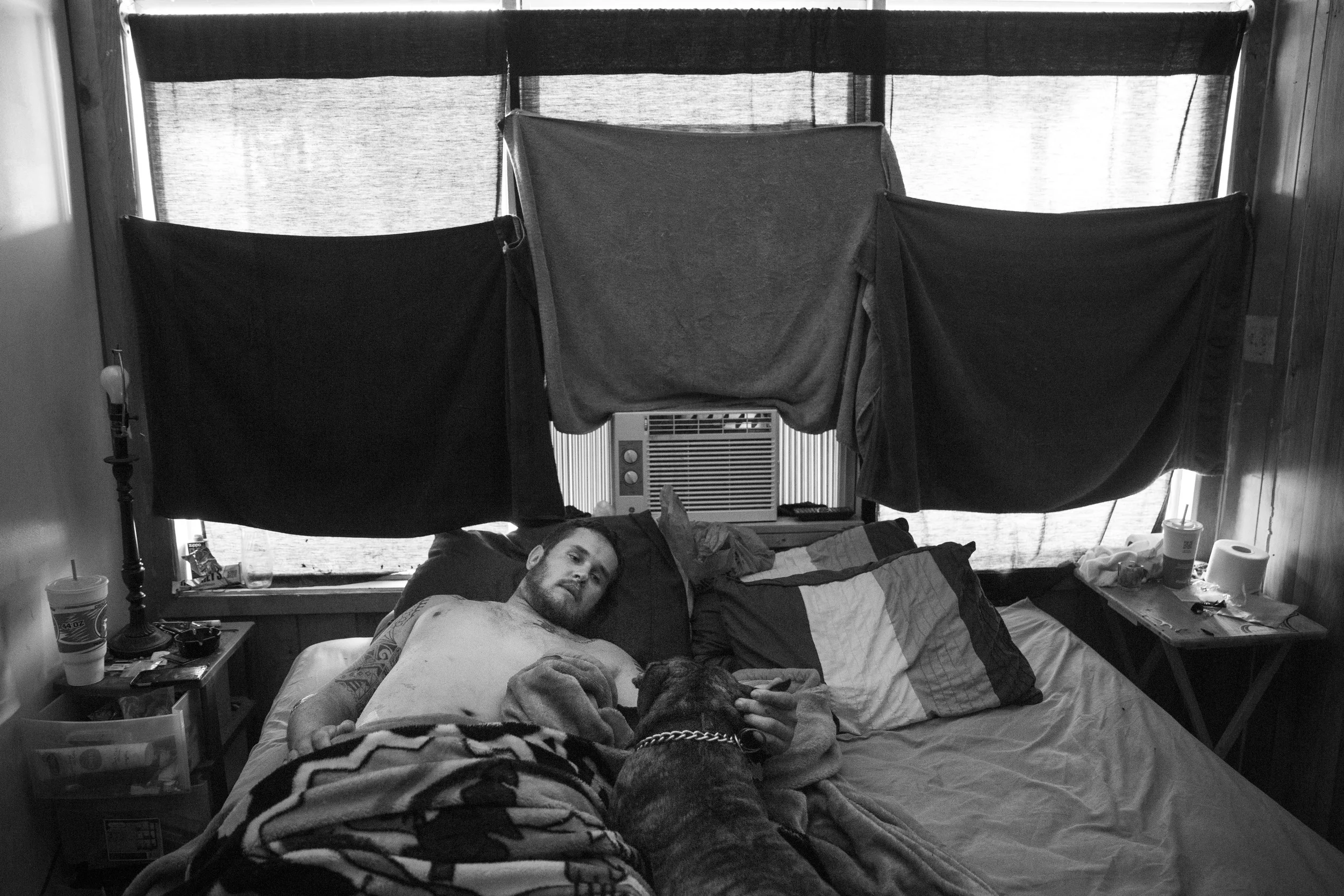  Devin Meurer, a former U.S. Marine, lays in bed with his dog Rocco in his apartment in Pleasanton, Texas, U.S. on August 6, 2015.  Meurer is facing eviction after getting in a motorcycle accident and losing his third oil field job since December 201