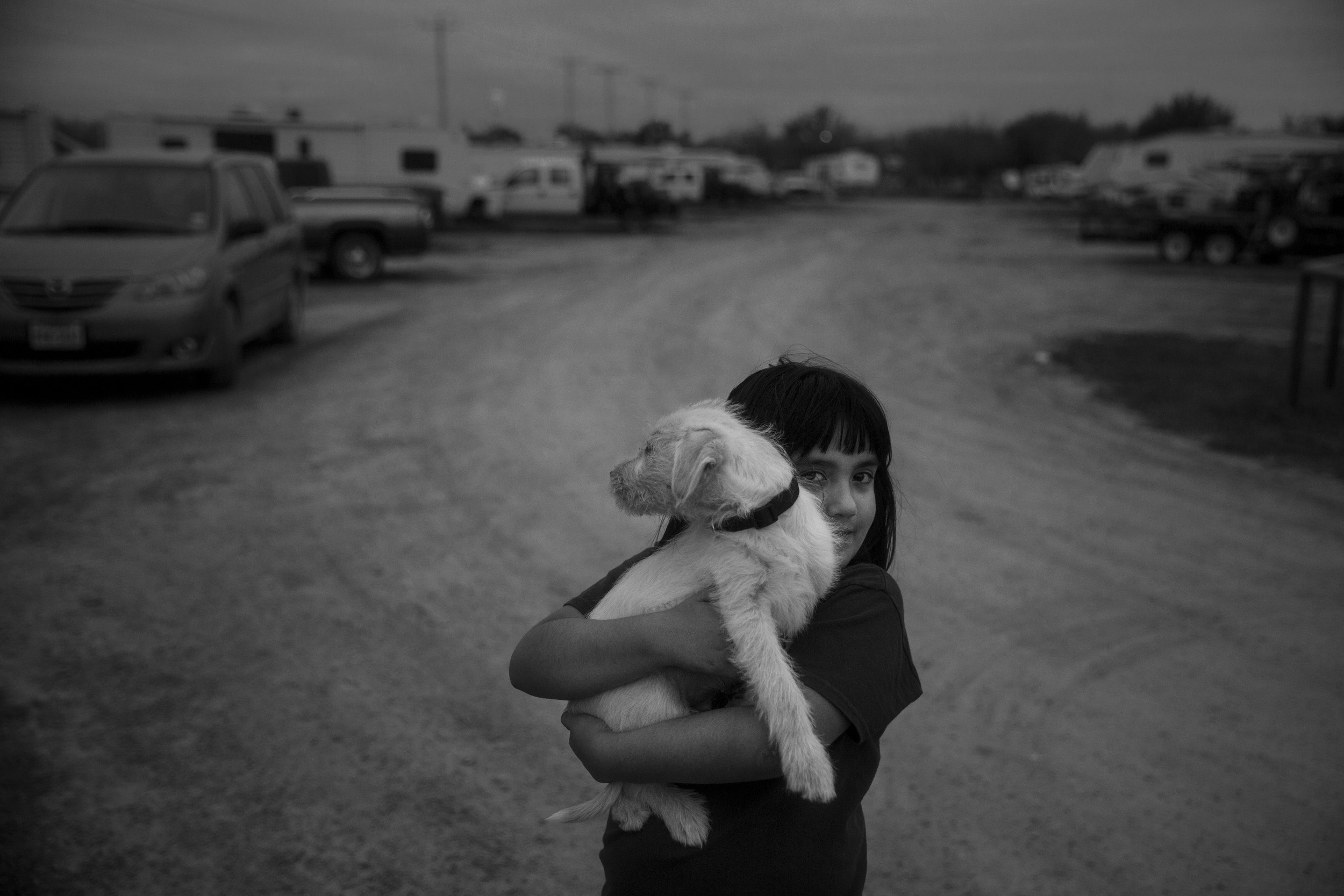  Bianca Chaires, 8, holds her family's puppy Brisket as she walks down the road that winds through the Cotulla RV Park in Cotulla, Texas, U.S. on March 7, 2015.  The RV park serves the oil field workers and their companies who want to have a more aff