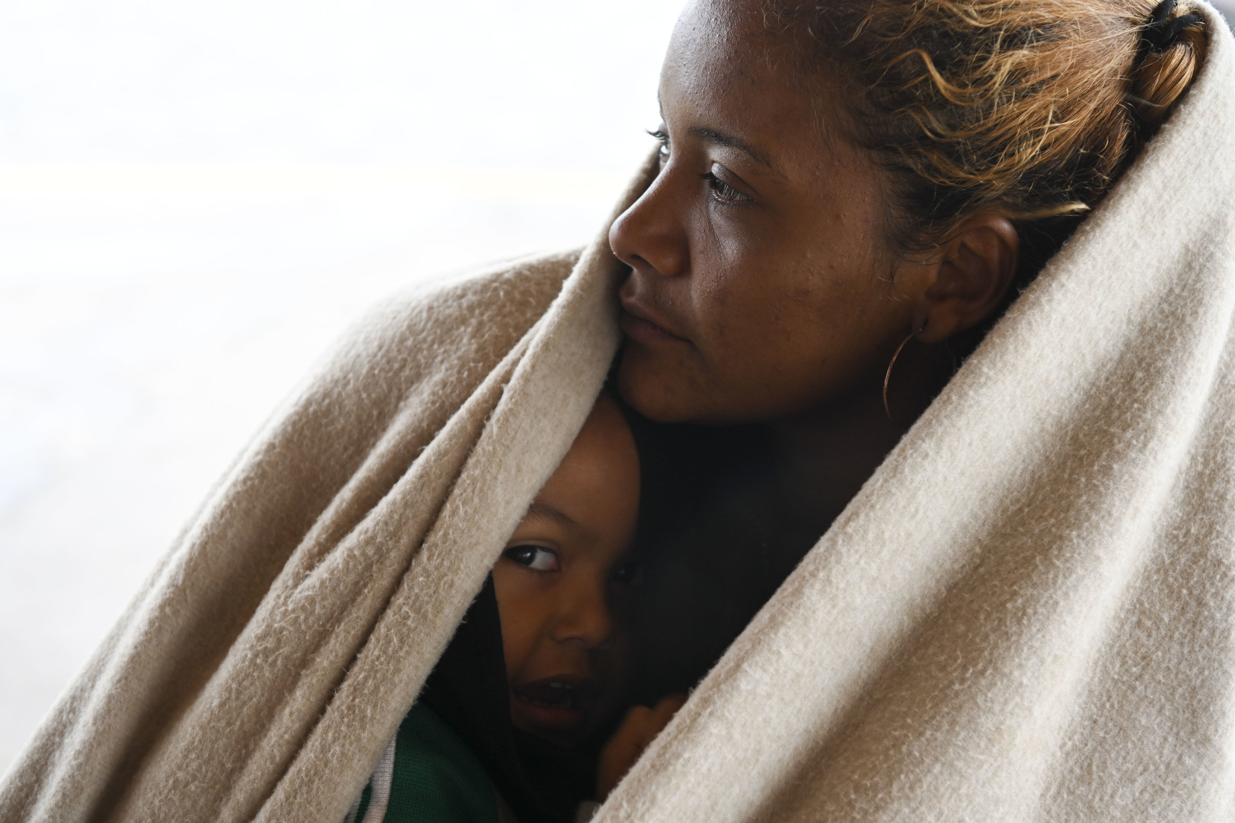 Cindy Romero, 24, from Honduras, holds her son Jason Velasquez, 2, and shields him from the cold winds coming off of the Pacific ocean as they wait with friends at the beach on November 29, 2018 in Tijuana, Mexico. They were weighing their options and deciding whether they should cross the border illegally at the beach to ask for asylum.