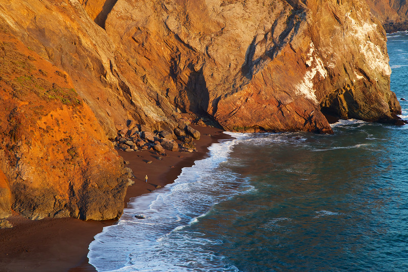 The golden light of sunset brightens the beach for a lone walker