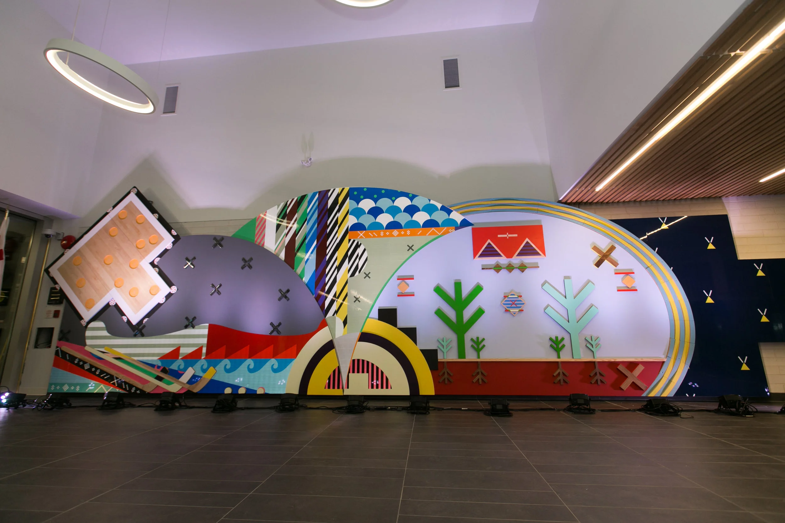 Pjila'si, 2019 Zatzman Sportsplex , Dartmouth Materials: Oak, walnut, maple, Labradorite, steel, acrylic paint, ash, plexiglass, 3M reflective print on Aluminum panels Dimensions: 35’x10’x2’ Photo: Chantal Routhier Installation commissioned by City of Halifax Regional Municipality Project managed by IOTA STUDIOS