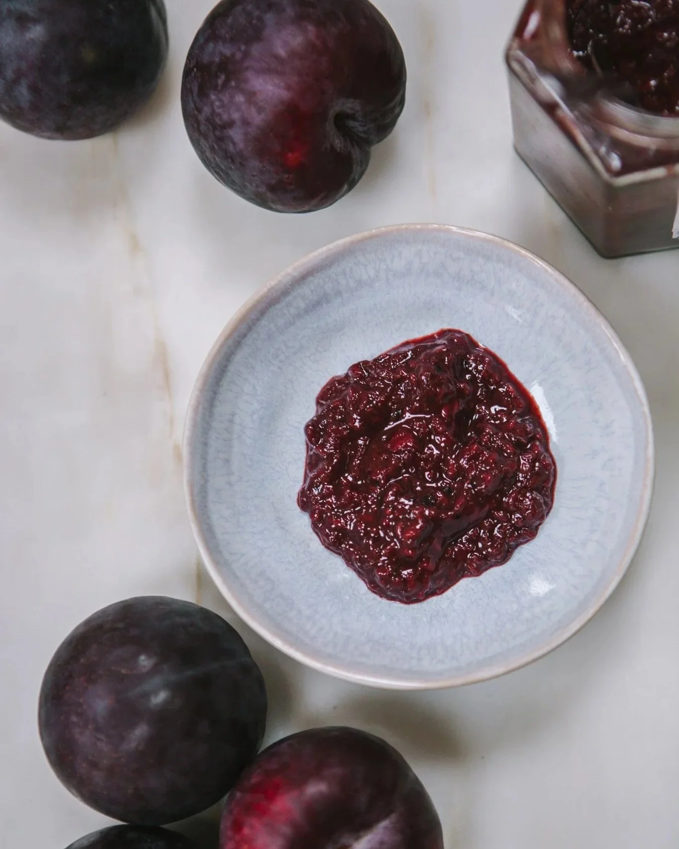 Plum jam with fresh plums and jam jar