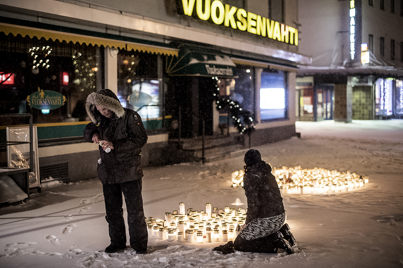 People putting lights on the ground in memory of the three women who were killed by a gunman outside a restaurant in Imatra, Finland. 
