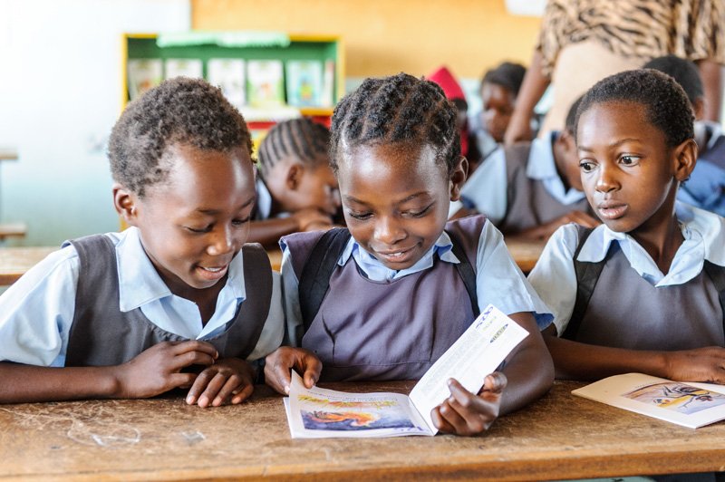 Choma Primary school three pupils reading and smiling.jpg
