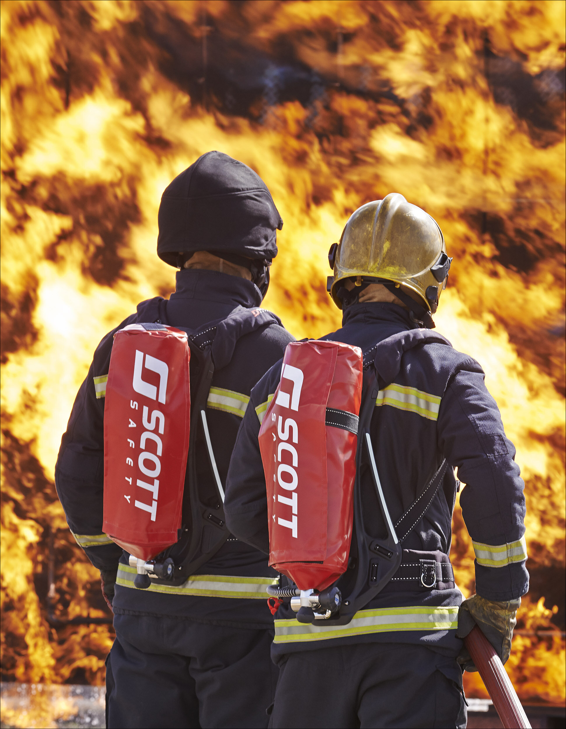 Back view of two firefighters wearing 3M Scott Safety respirators in a fire 