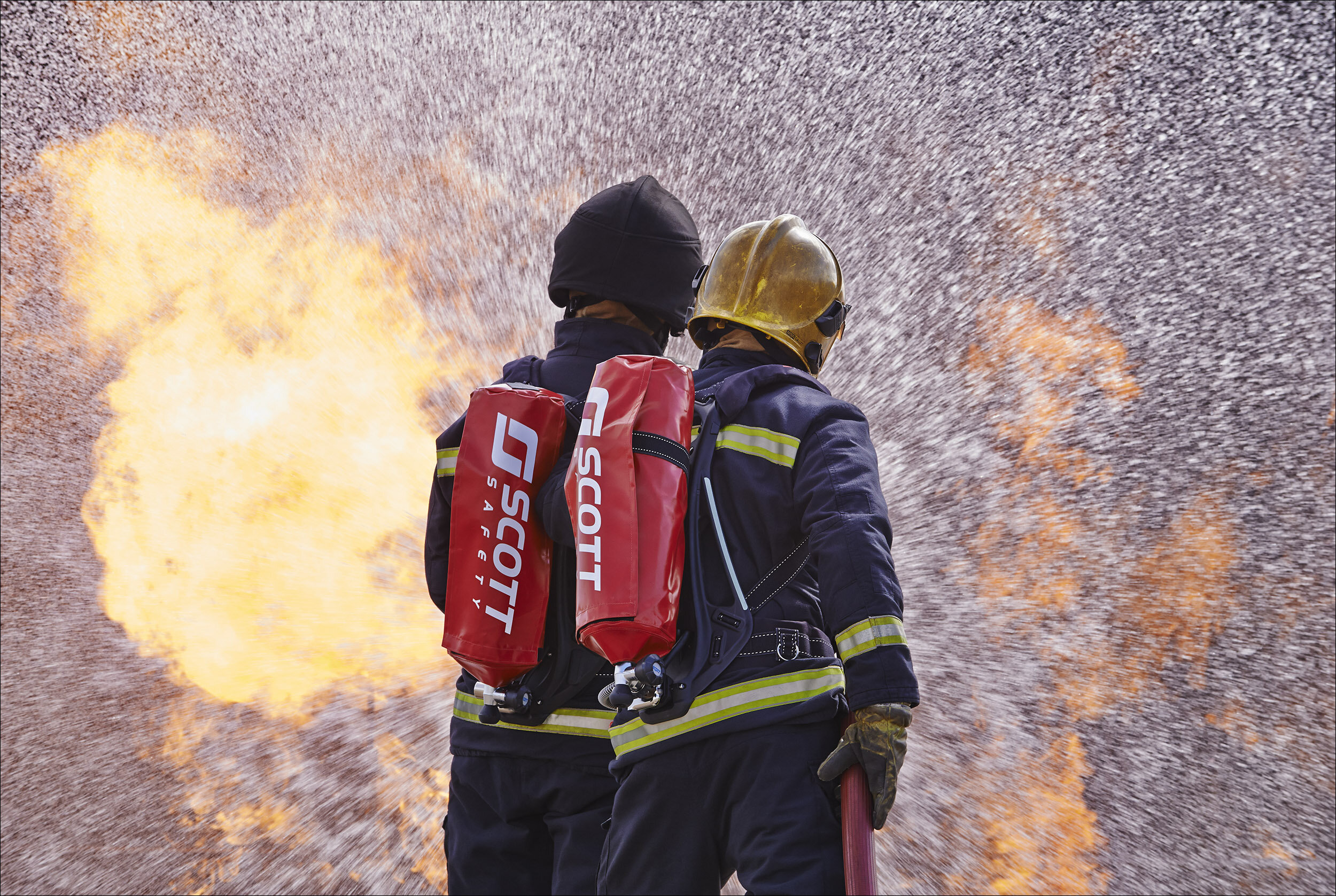 Two firefighters firefighting wearing 3M Scott Safety respirators