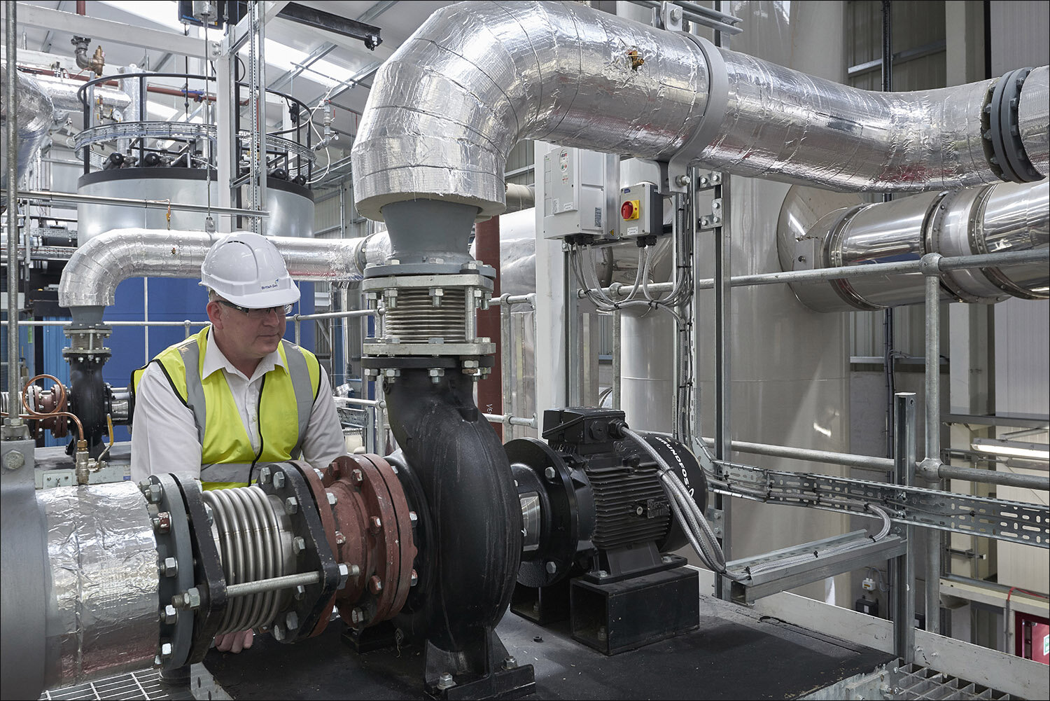 British Gas engineer working inside a factory with steel pipework