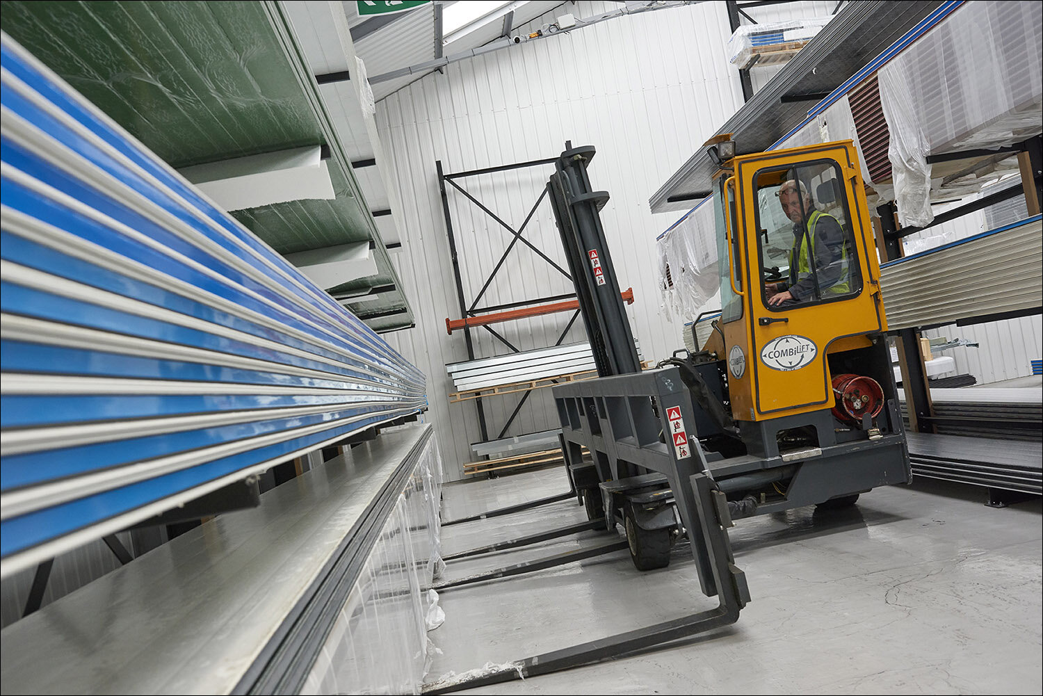 Industrial forklift lifting roller shutter door panels in a factory