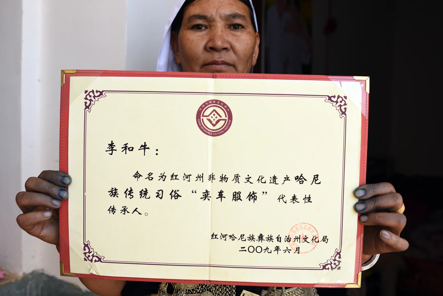 Li He Niu shows the her intangible cultural heritage inheritor certificate. Dayangjie town, Yunnan 2017.