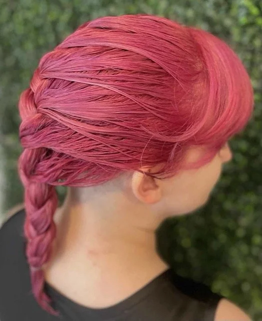 Side and back view of bright pink hair styled in a sleek braid with soft side bangs, created by a Chroma Salon stylist in Seattle.