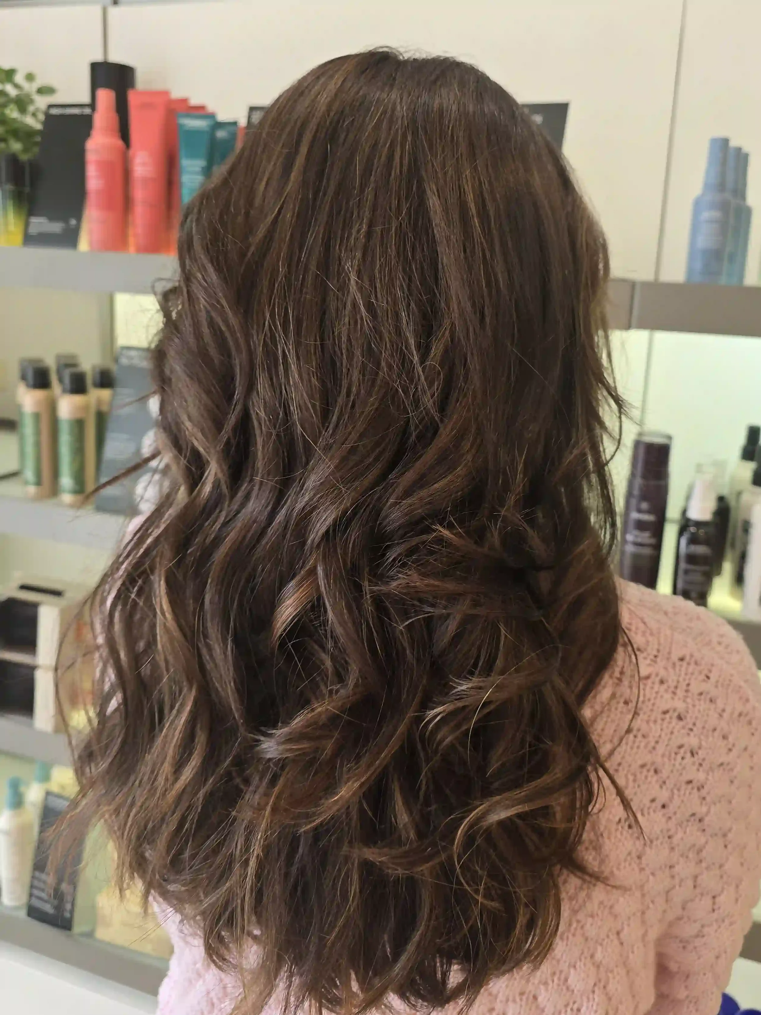 Long brunette hair with dimensional balayage featuring soft caramel ribbons, a seamless blended finish, and loose, touchable waves. This natural-looking brunette color adds depth, shine, and movement while creating a low-maintenance, lived-in result.
