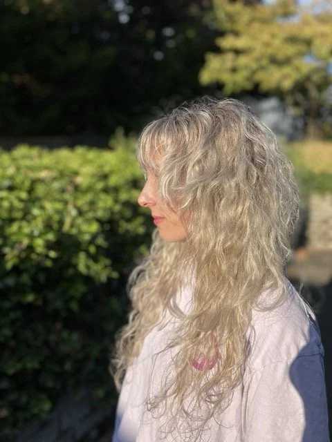 Golden blonde curly hair styled at Chroma Salon Seattle. Our expert curly hair stylists in Seattle specialize in enhancing natural curls with shine, definition, and volume for healthy, beautiful results.