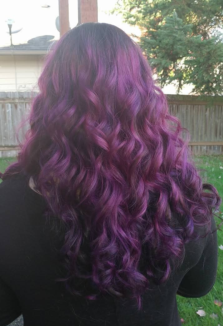 Vibrant vivid purple fashion color with rich jewel-tone dimension and a seamless saturation from roots to ends. Styled with long, cascading curls to showcase shine, movement, and depth, this bold creative color delivers a striking, high-impact finish