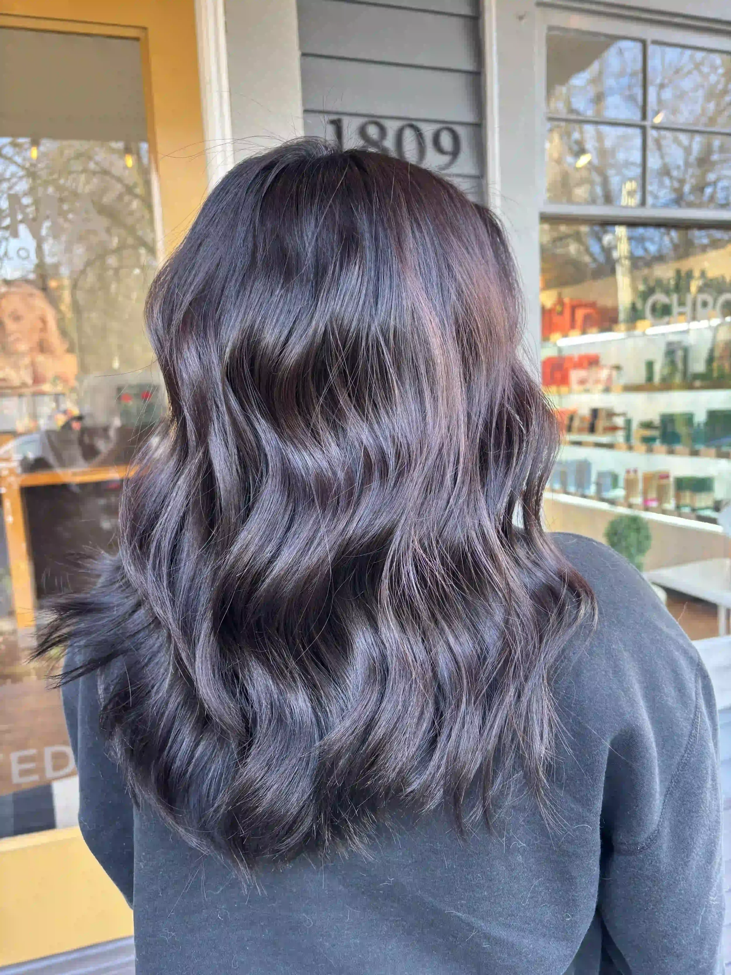 Glossy dark brunette hair with soft, polished waves, created by Alpin at Chroma Salon Queen Anne Seattle for rich shine and healthy-looking dimension.