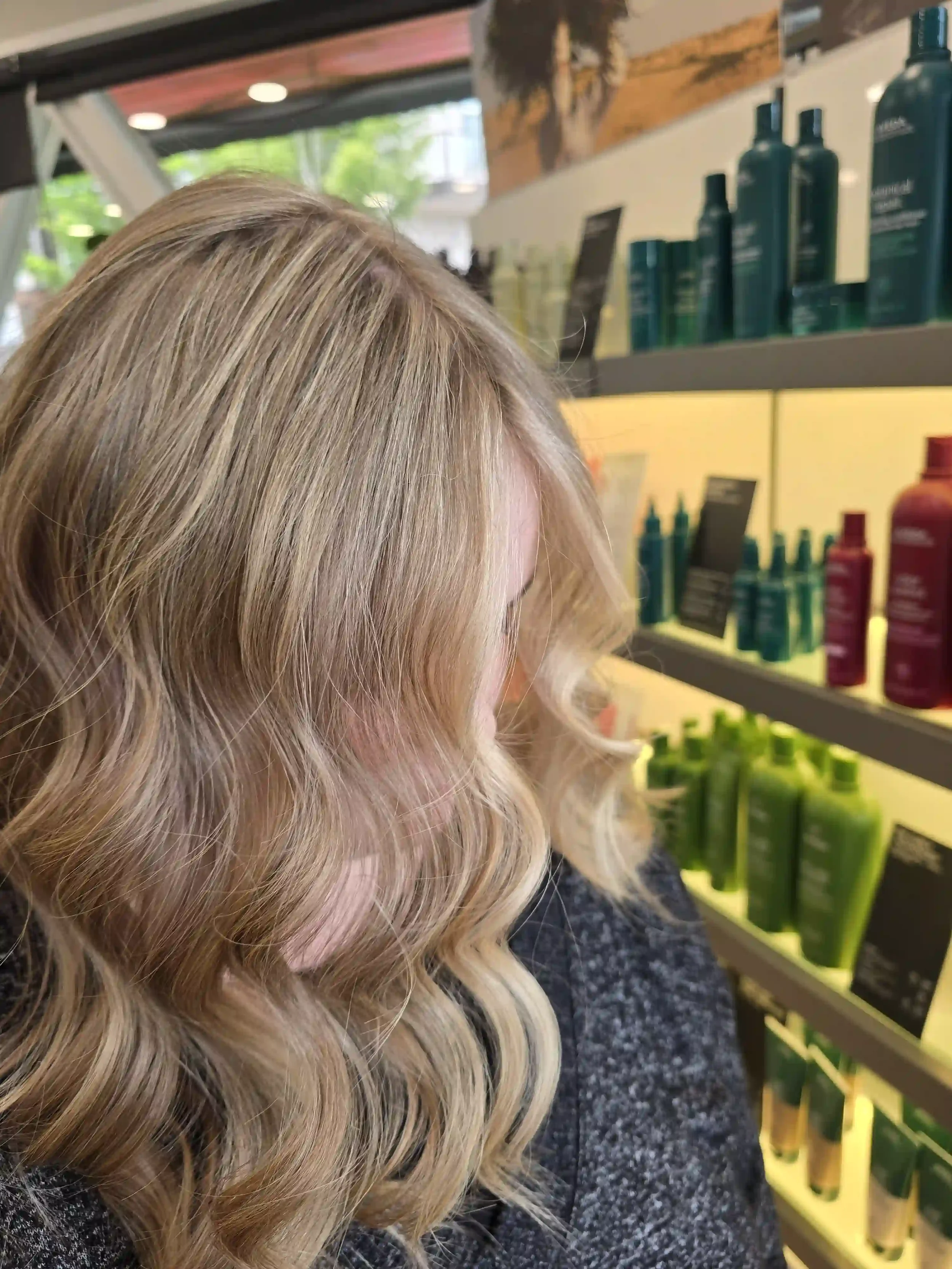 Shoulder-length dimensional blonde balayage with a soft shadow root, bright face-framing highlights, and loose, modern waves. This lived-in blonde color creates seamless dimension, natural depth, and a low-maintenance grow-out while enhancing shine a