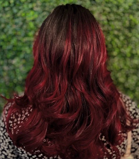 Deep burgundy red balayage with soft waves and long layers, created by Stormi at Chroma Salon Queen Anne Seattle for rich, dimensional color and shine.
